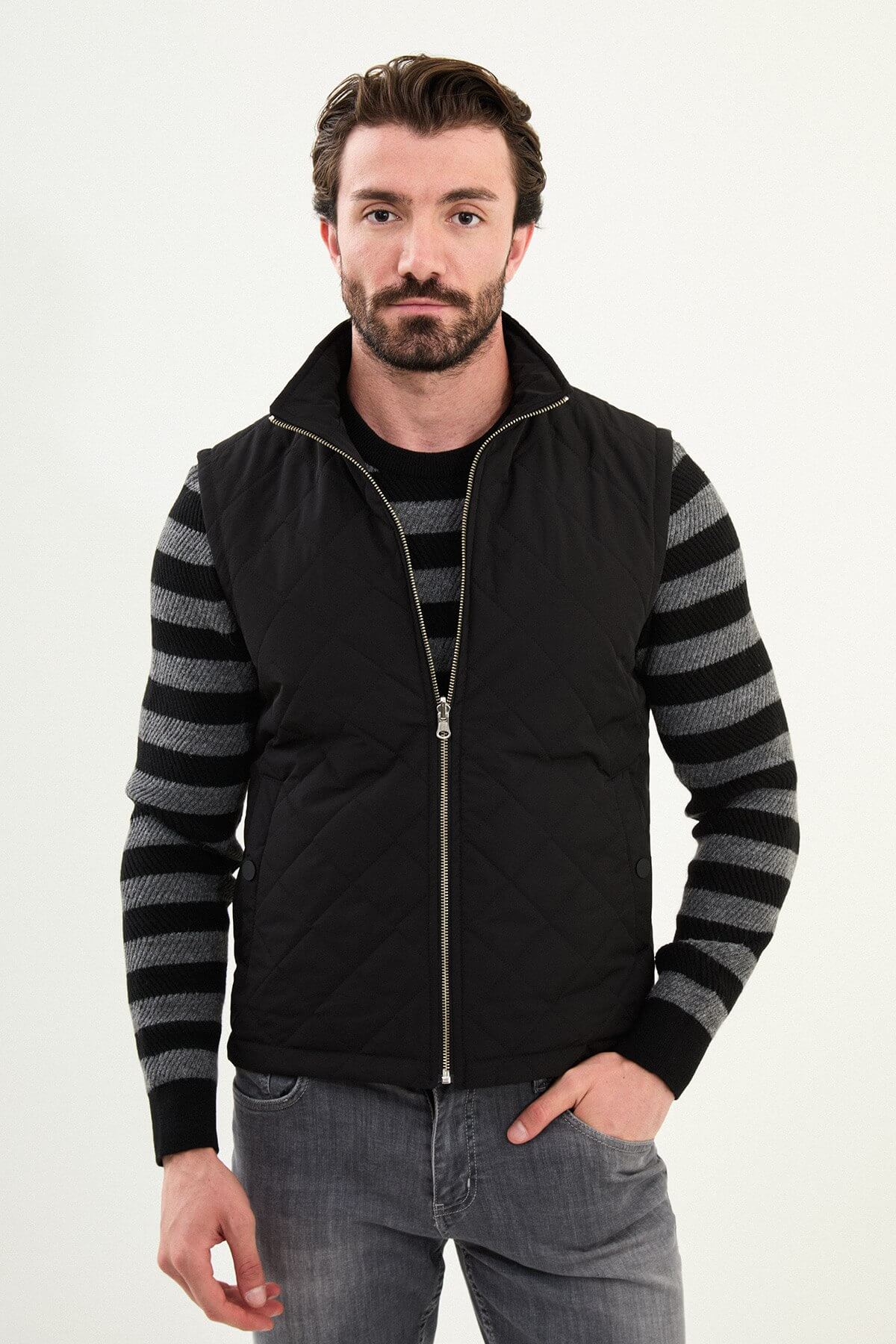 Men’s matte black technical vest with a stand collar and snap-flap utility pockets, designed for winter layering.