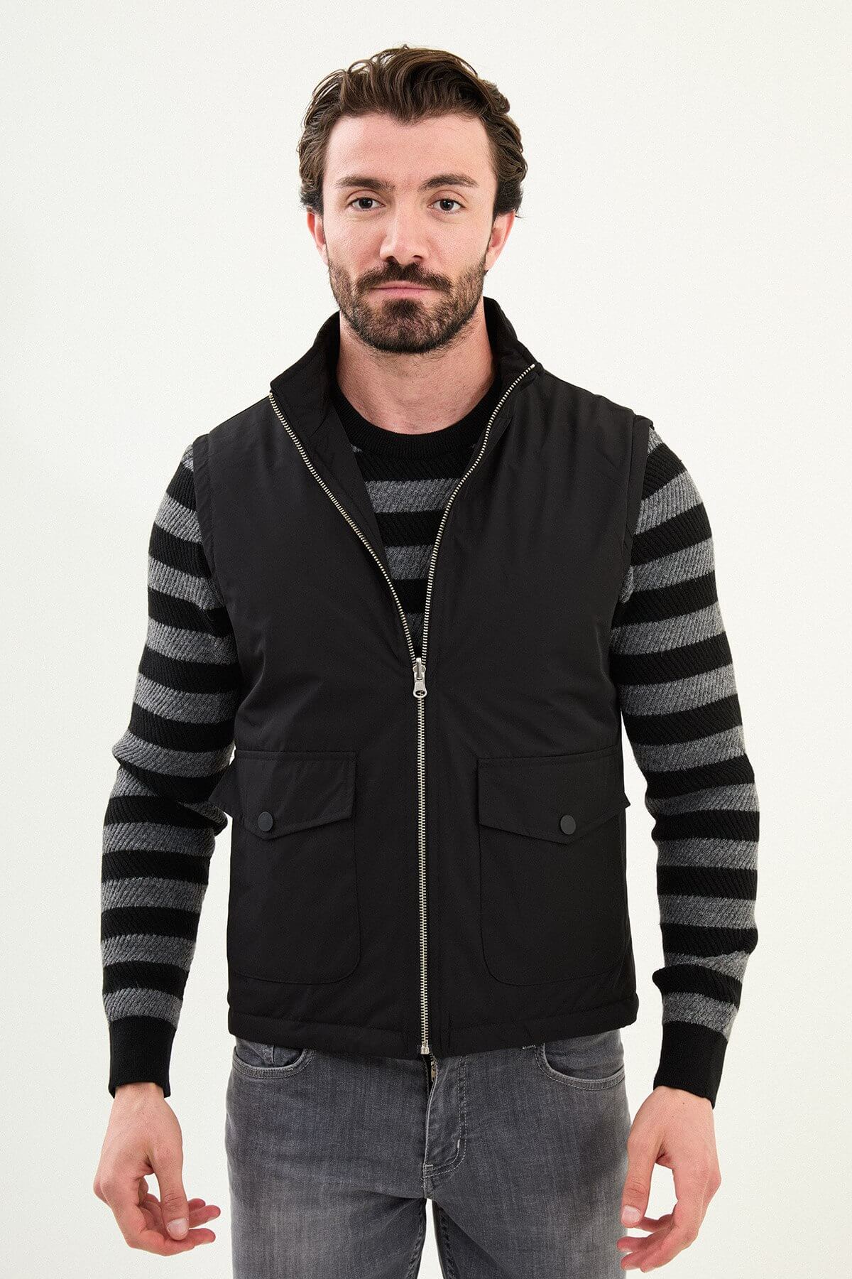 Men’s matte black technical vest with a stand collar and snap-flap utility pockets, designed for winter layering.