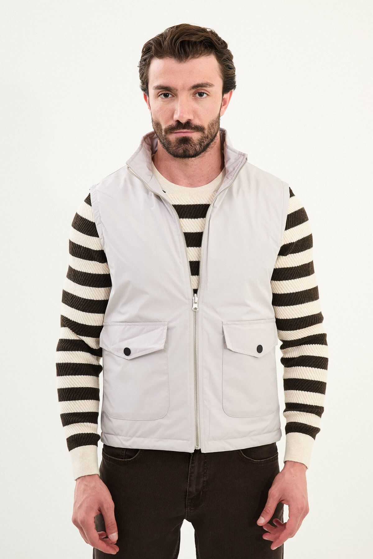 Light gray matte men’s technical utility vest with a stand collar, zip front, and two oversized snap-flap cargo pockets.