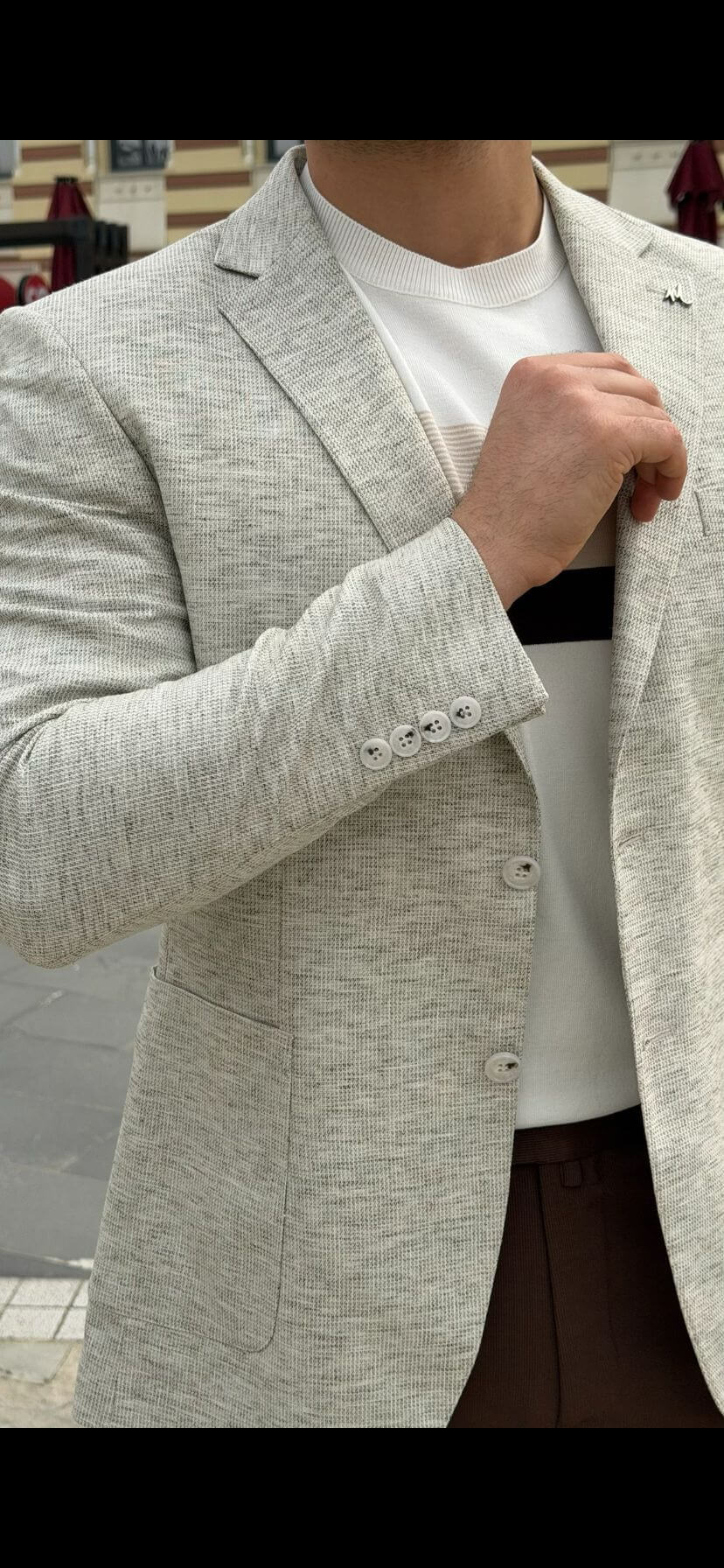 Men’s light beige slim-fit knitted blazer with a buttoned front and a modern, tailored silhouette, worn with a white t-shirt and brown trousers