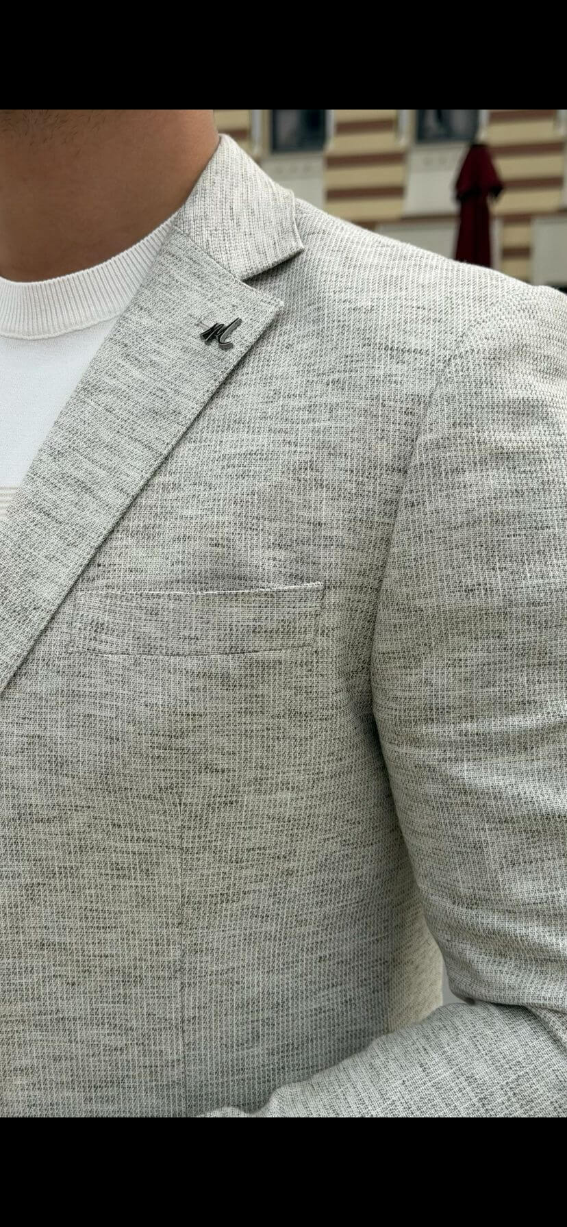 Men’s light beige slim-fit knitted blazer with a buttoned front and a modern, tailored silhouette, worn with a white t-shirt and brown trousers