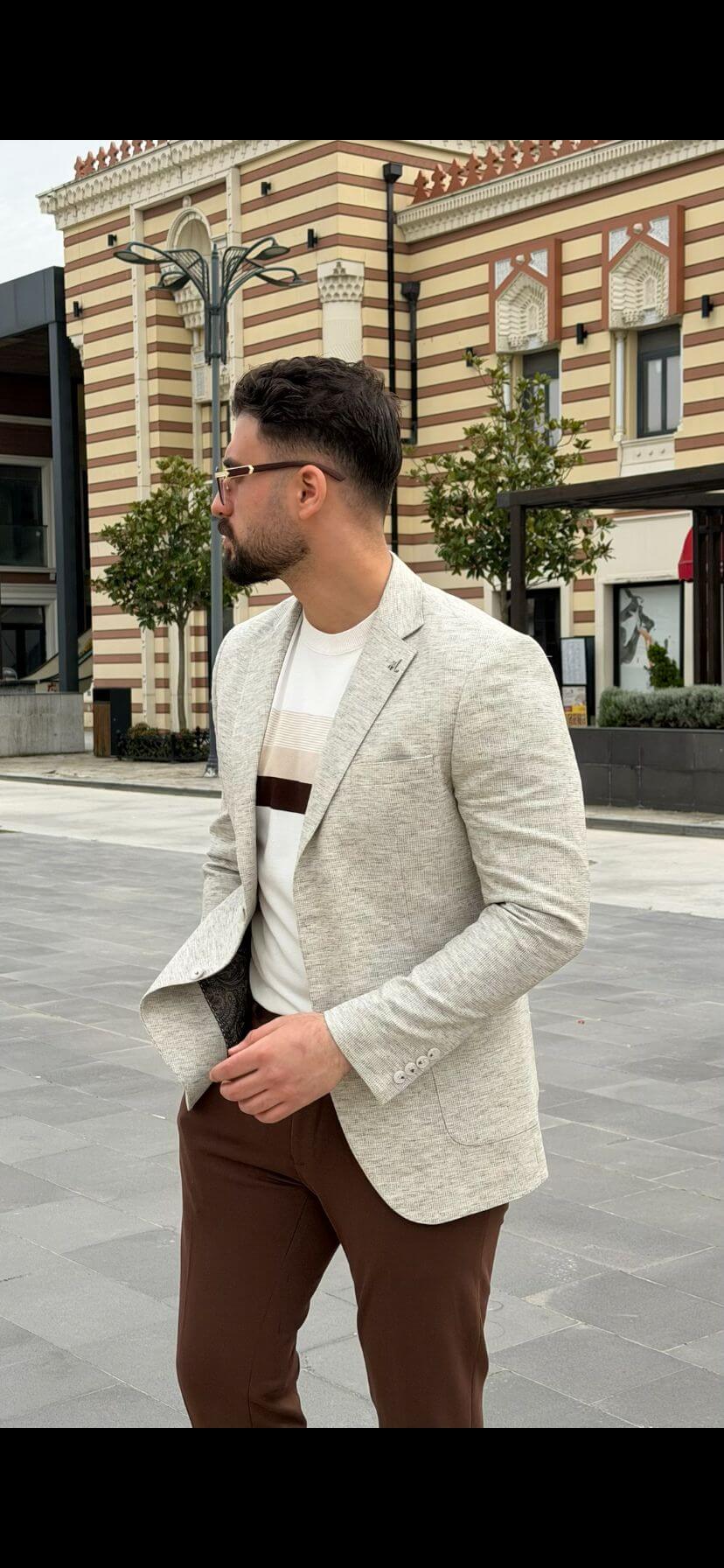 Men’s light beige slim-fit knitted blazer with a buttoned front and a modern, tailored silhouette, worn with a white t-shirt and brown trousers