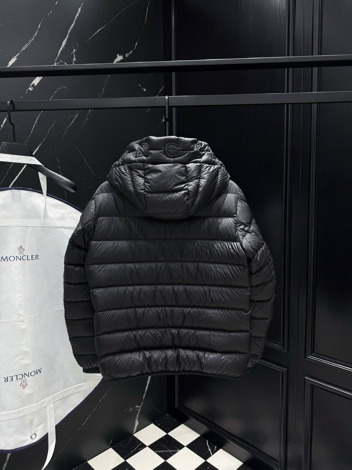Black shiny down puffer jacket with hood, front zipper, and quilted padding, Moncler-inspired design.