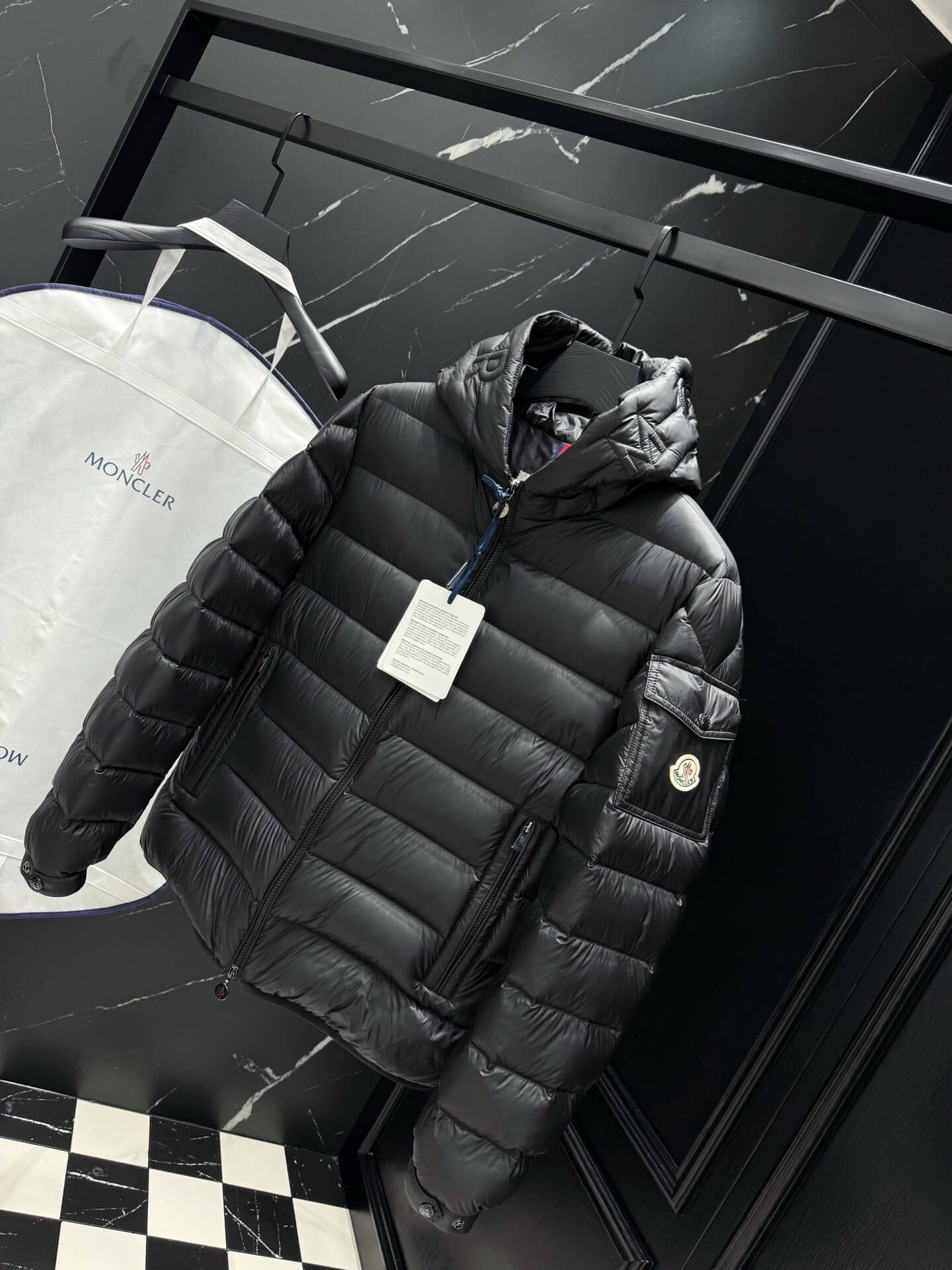 Black shiny down puffer jacket with hood, front zipper, and quilted padding, Moncler-inspired design.
