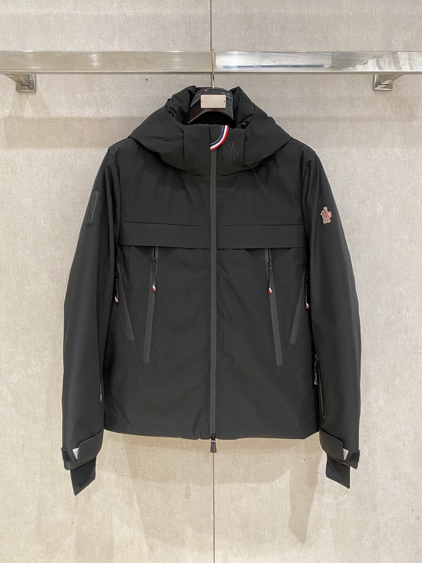 Black hooded down jacket with zip pockets and technical shell, Moncler Grenoble Balmhorn-inspired design.