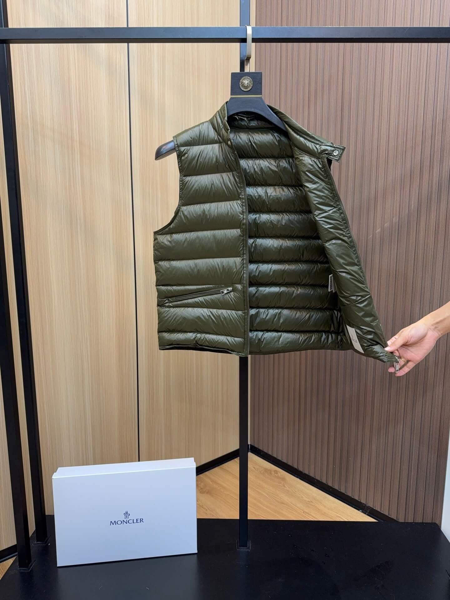 Green glossy down vest with chest logo patch and zippered pockets, Moncler Gui-inspired design.