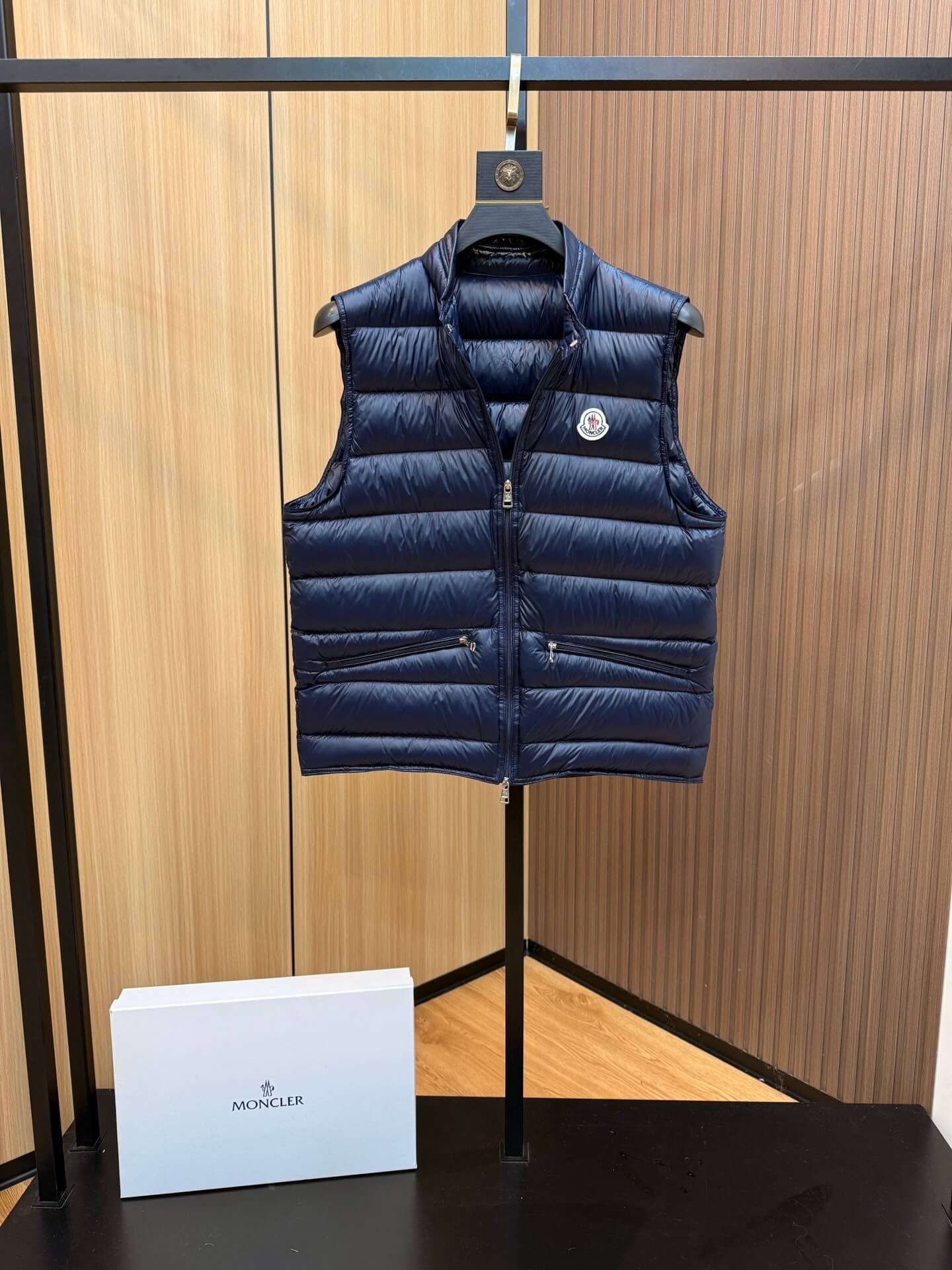 Navy blue glossy down vest with chest logo patch and zippered pockets, Moncler Gui-inspired.