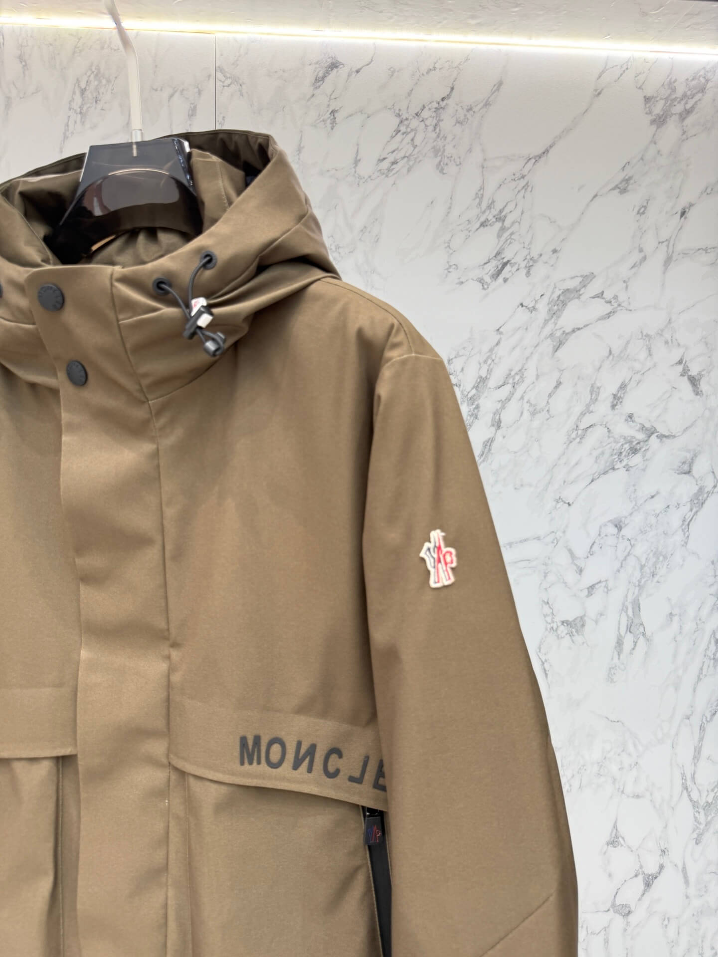 Brown hooded technical jacket with front snap closure and zippered pockets, Moncler-inspired design