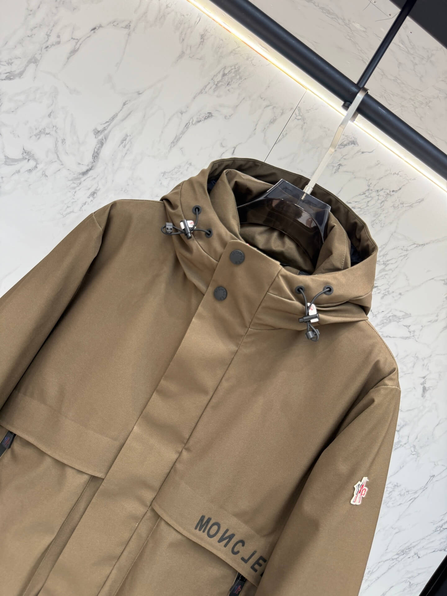 Brown hooded technical jacket with front snap closure and zippered pockets, Moncler-inspired design