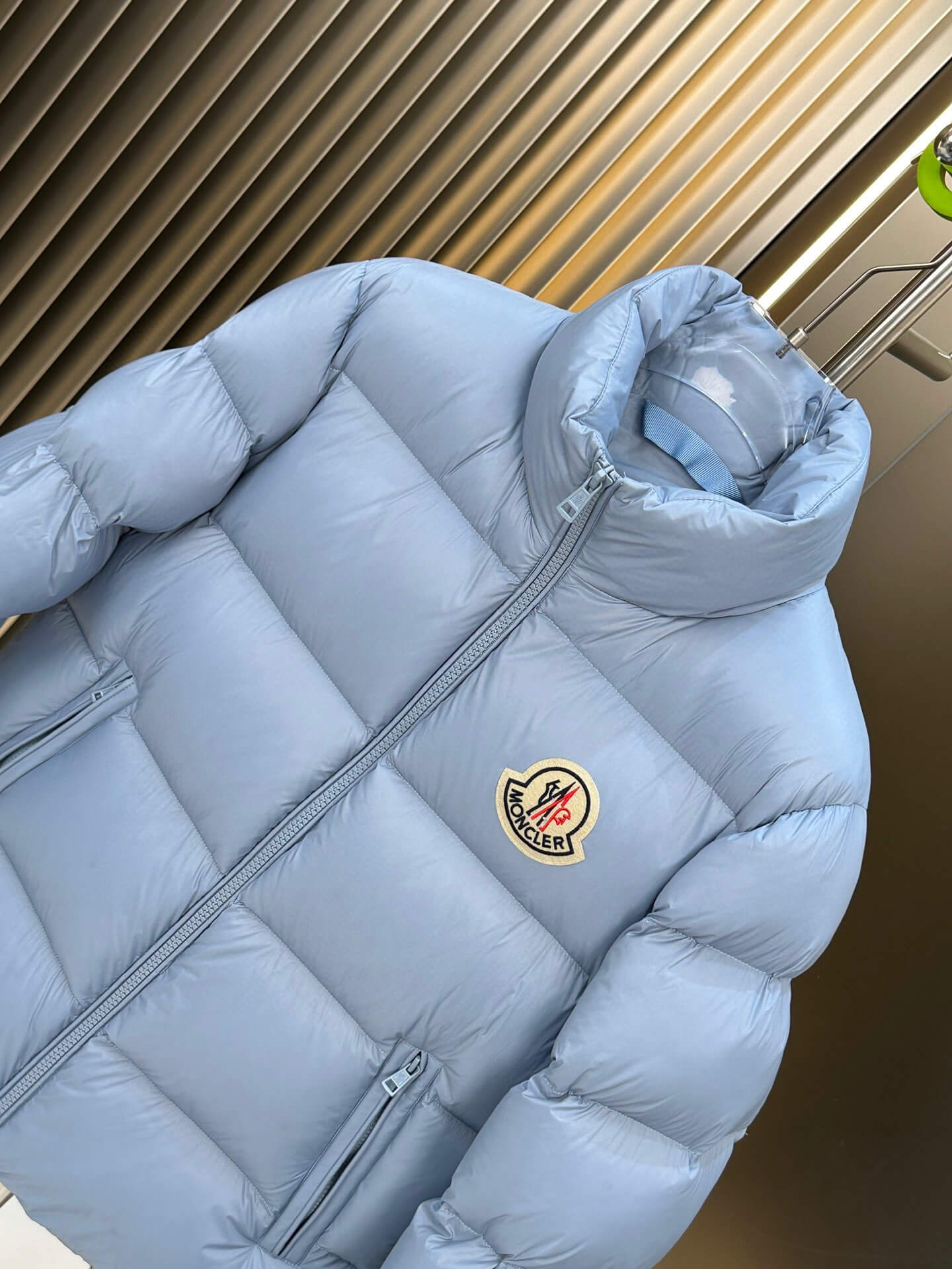 Moncler Maya Blue Hooded Short Down Jacket featuring a sky-blue quilted design, front zip closure, and Moncler logo patch on the chest.