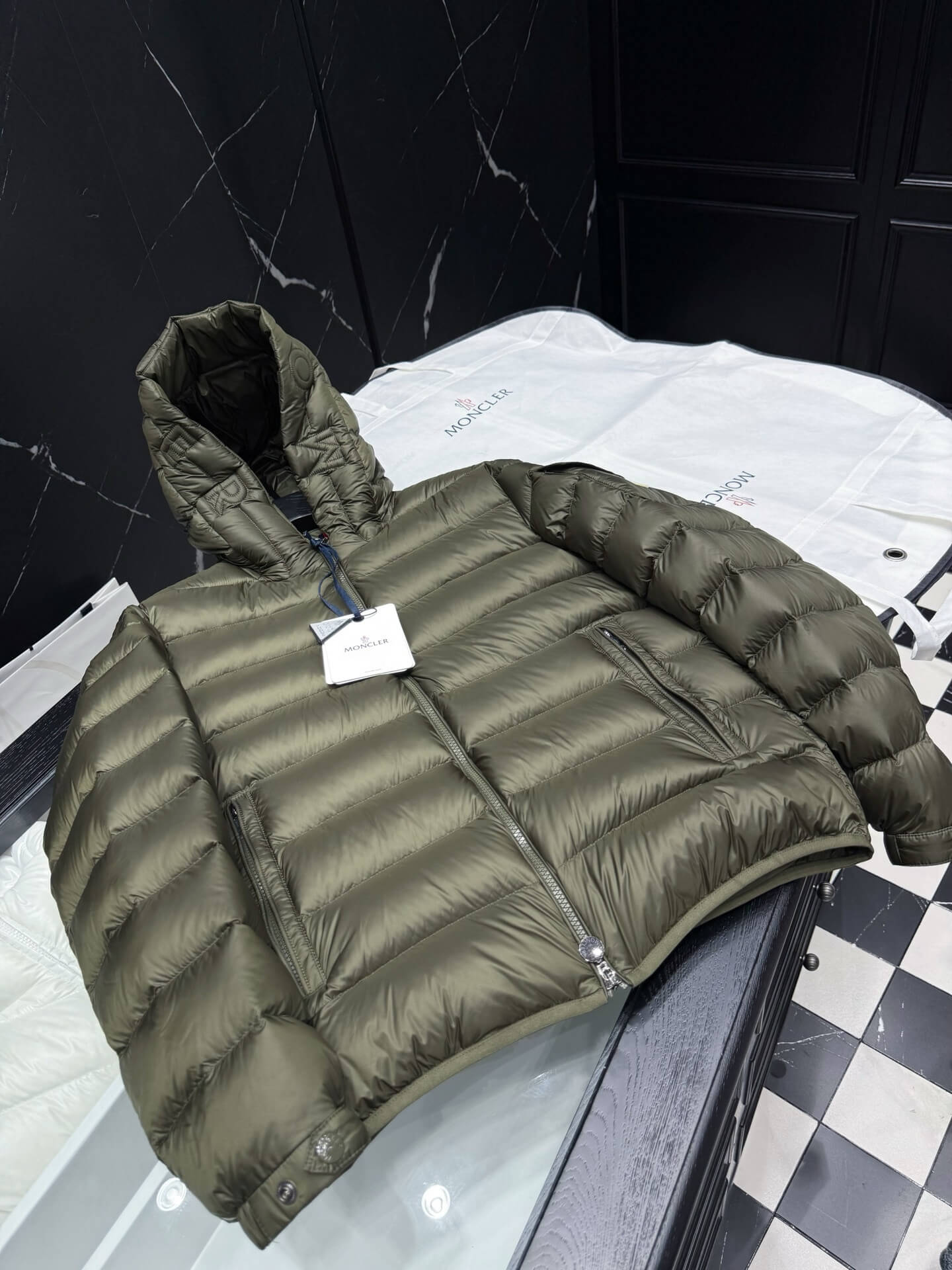 Green hooded glossy down jacket with quilted panels and zippered pockets, Moncler Maya-inspired design.