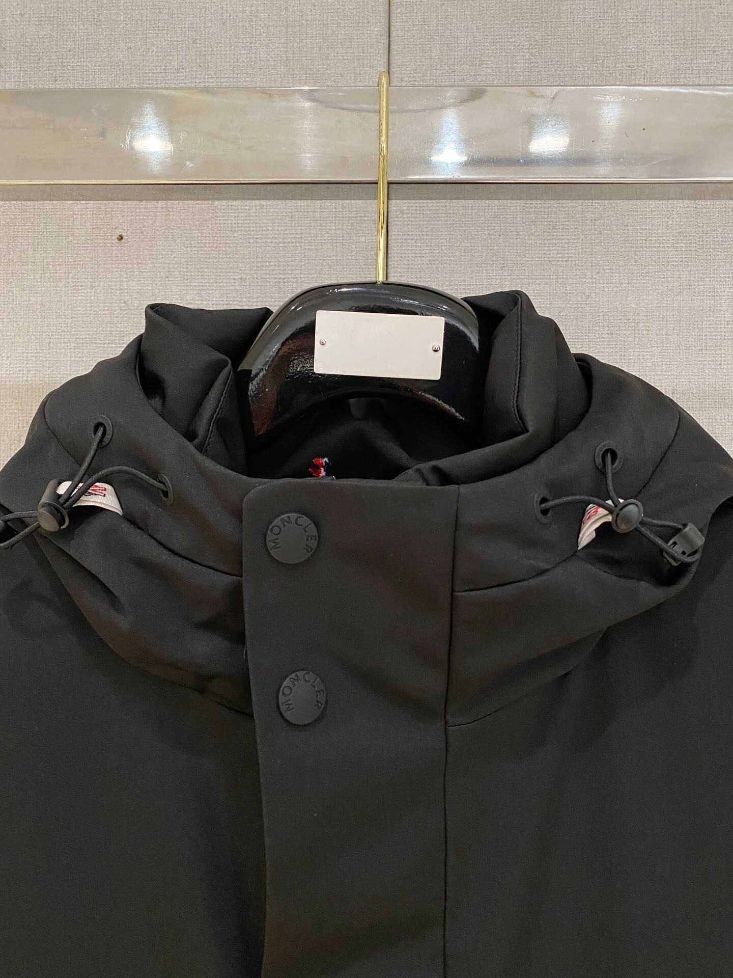 Black Moncler-inspired men’s Maya down jacket with quilted puffer design, detachable hood, and front zip closure, displayed on hanger.