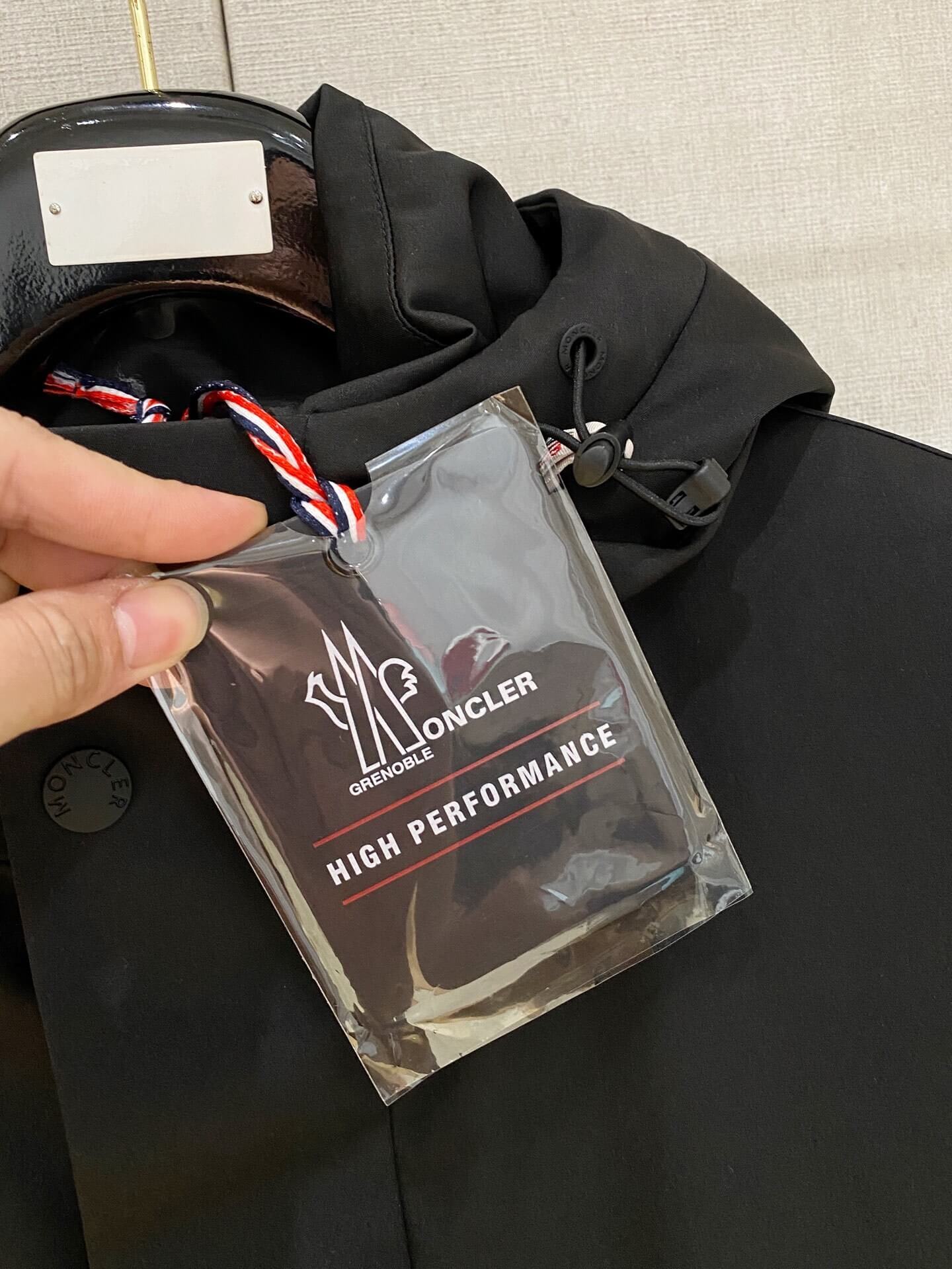 Black Moncler-inspired men’s Maya down jacket with quilted puffer design, detachable hood, and front zip closure, displayed on hanger.