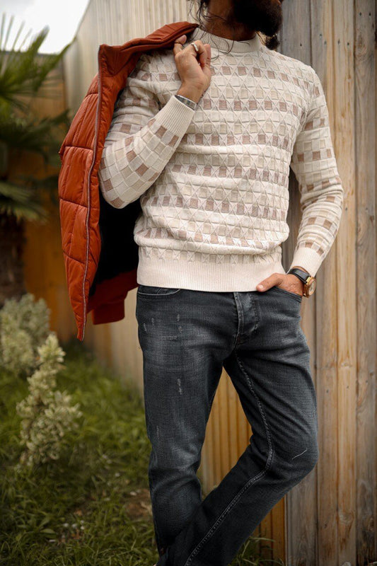 Man wearing a slim-fit beige knitwear sweater with geometric jacquard design, styled with dark jeans.