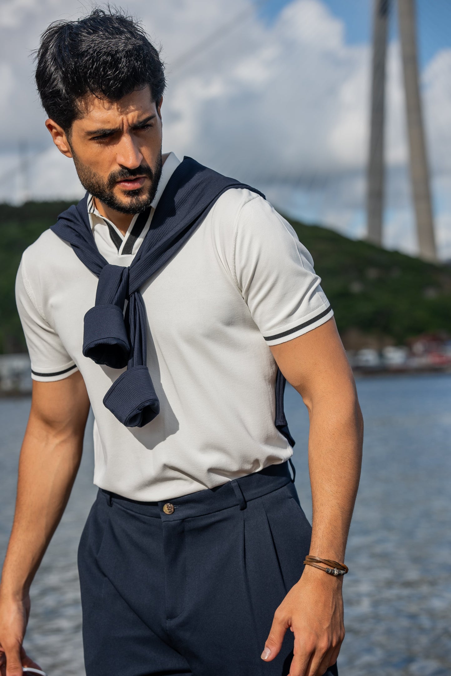 Stylish summer outfit featuring a white polo t-shirt, navy wide-leg trousers, and white sneakers, perfect for a breezy coastal stroll by the water.