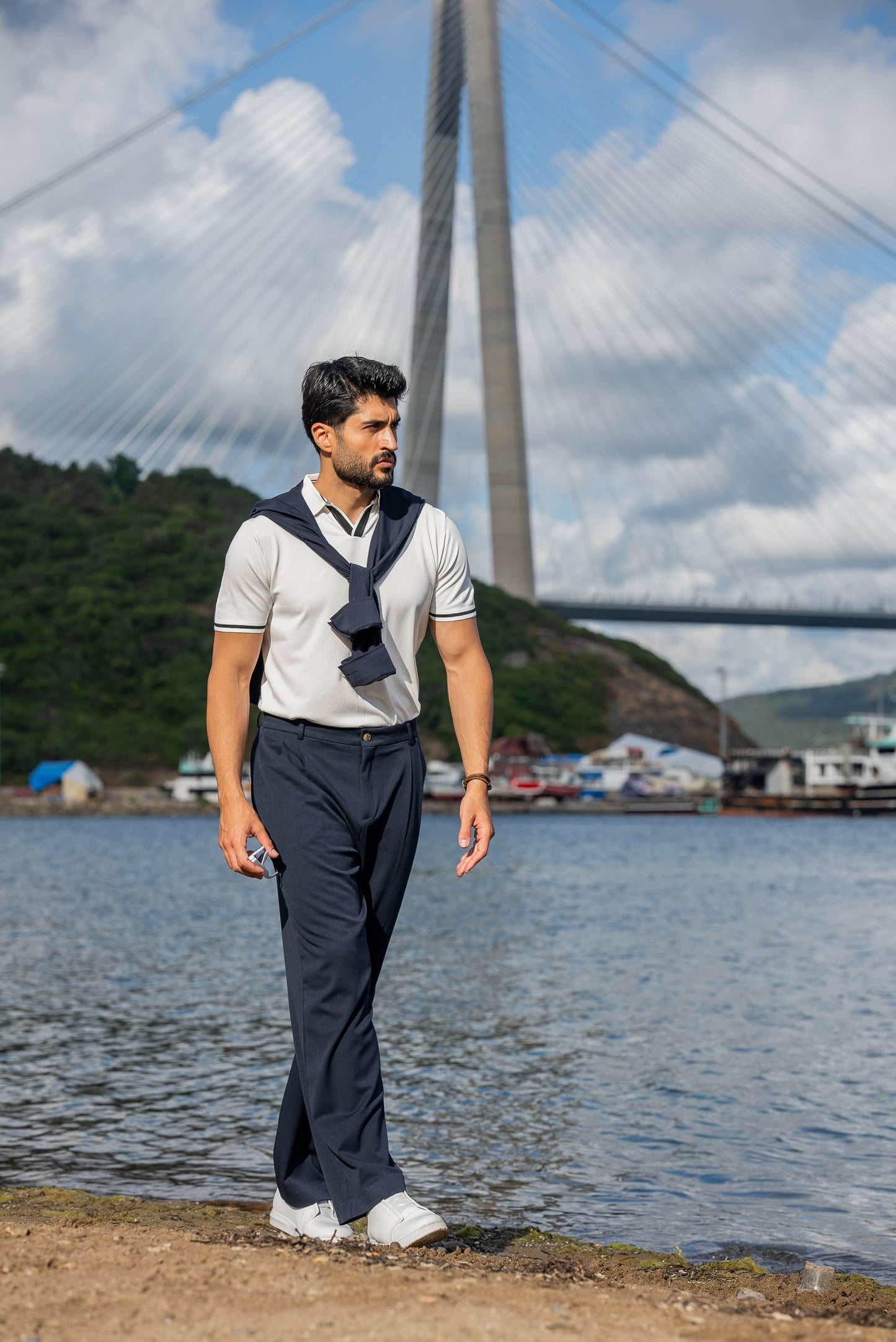 Stylish summer outfit featuring a white polo t-shirt, navy wide-leg trousers, and white sneakers, perfect for a breezy coastal stroll by the water.