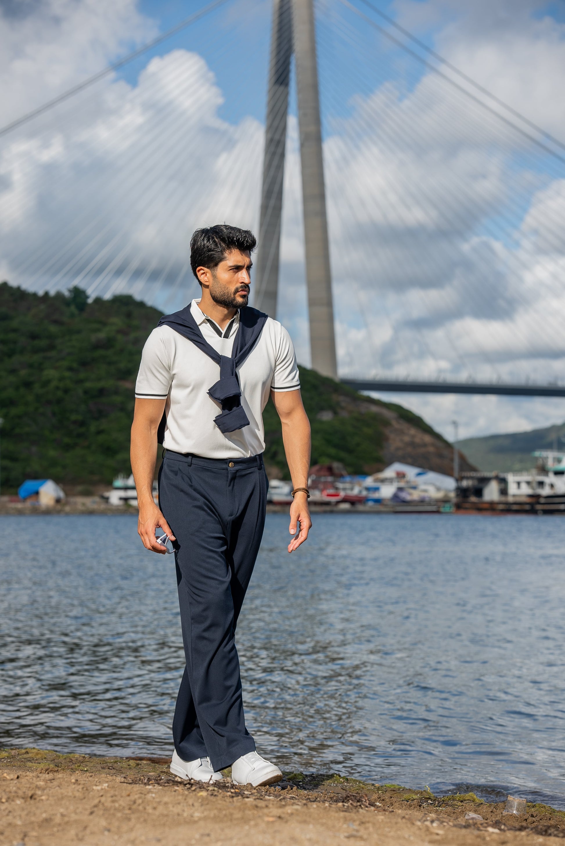 Stylish summer outfit featuring a white polo t-shirt, navy wide-leg trousers, and white sneakers, perfect for a breezy coastal stroll by the water.