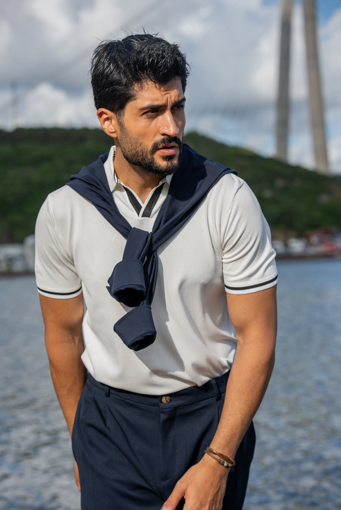 Stylish summer outfit featuring a white polo t-shirt, navy wide-leg trousers, and white sneakers, perfect for a breezy coastal stroll by the water.