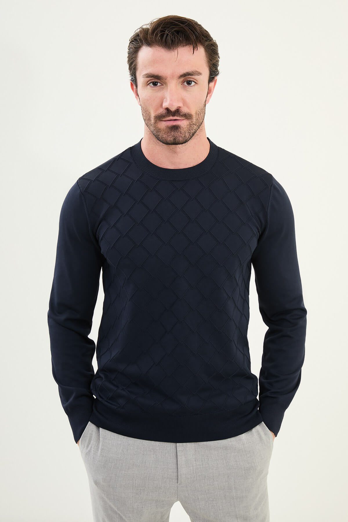 Men’s navy blue textured crew neck sweater with geometric knit pattern, slim fit smart casual knit styled with light gray trousers