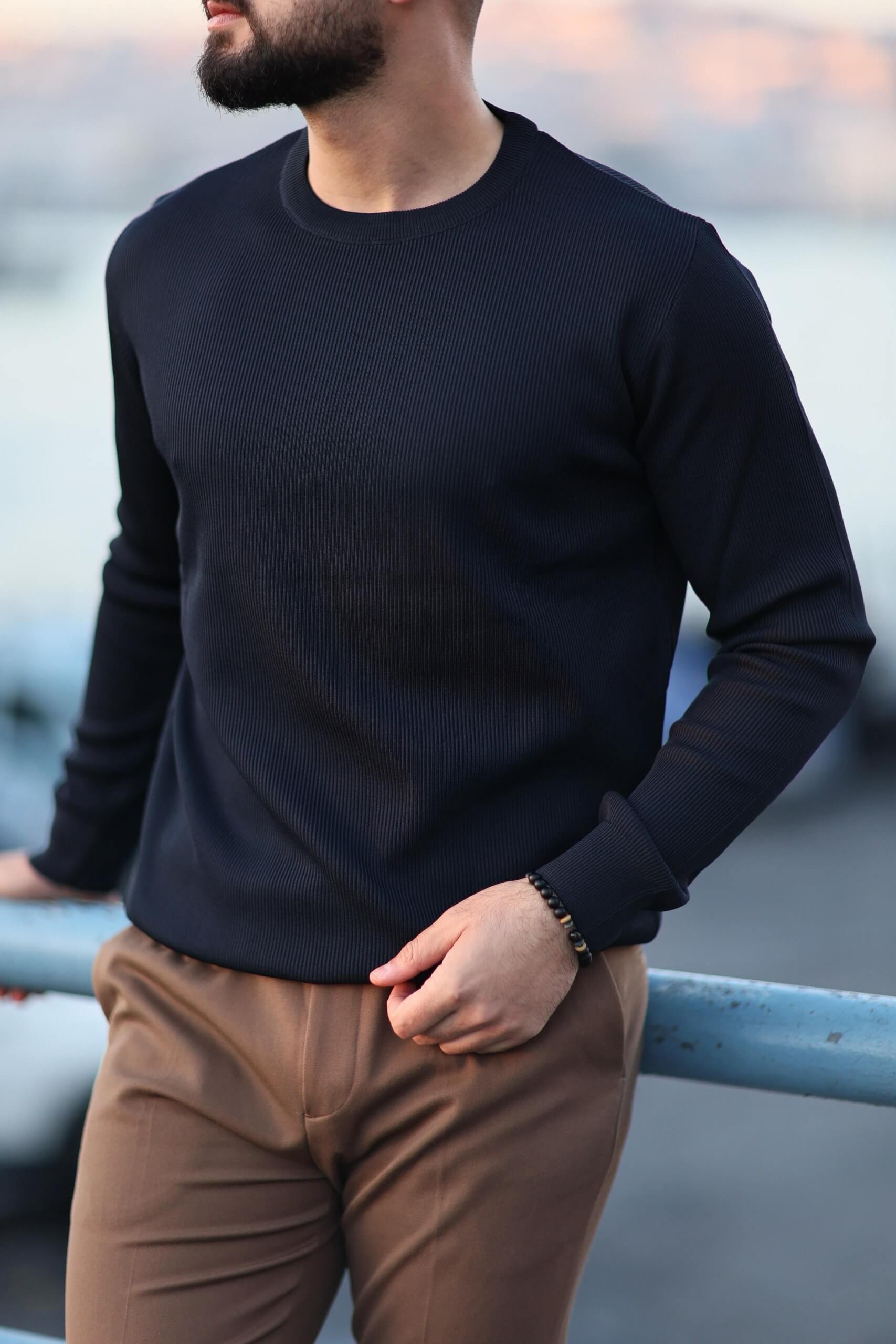 Men’s navy blue long-sleeve knit polo shirt worn outdoors, styled with camel slim-fit trousers