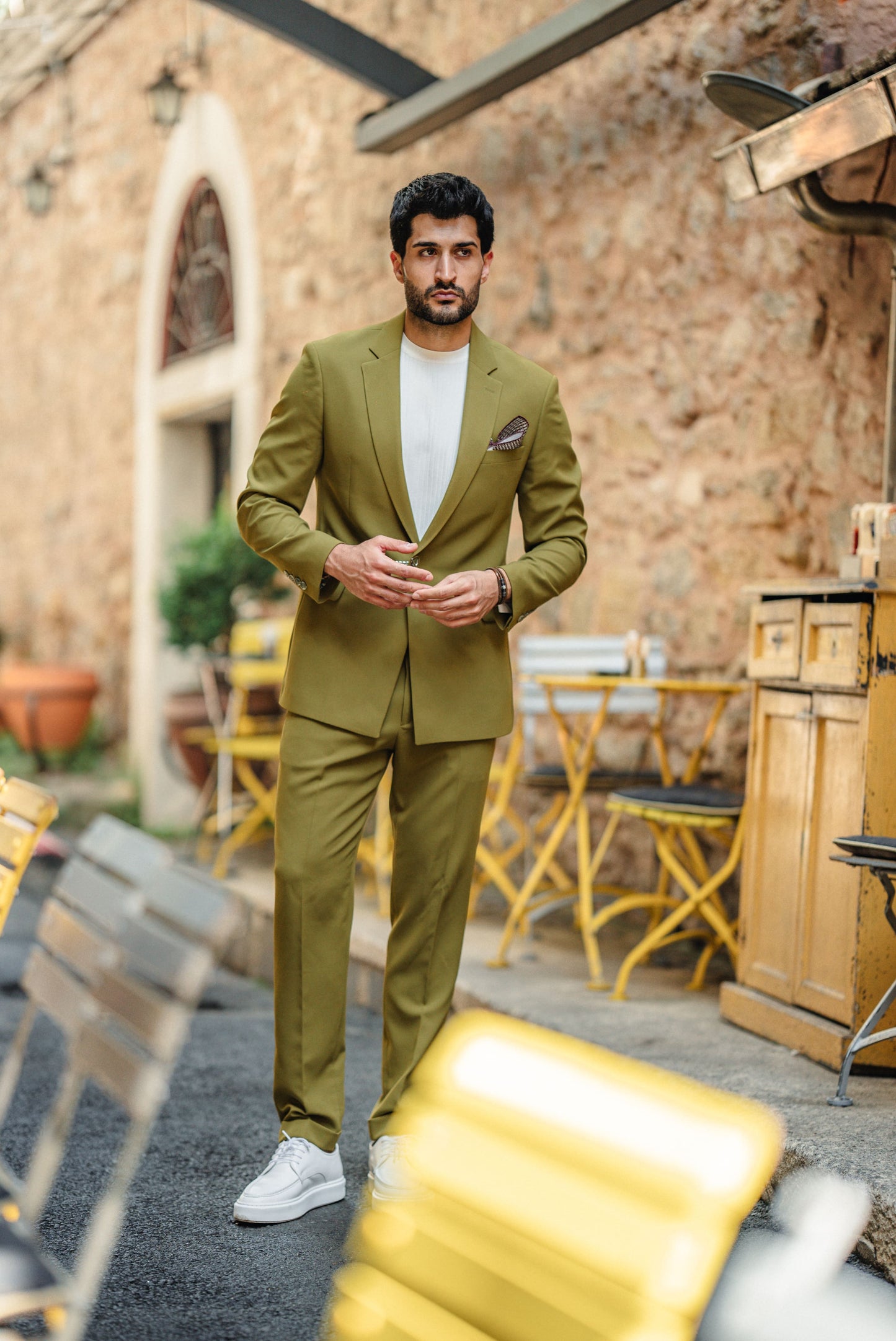 Man wearing the Bora Bora Olive Green Luxury Chain Detailed Suit with a white shirt and loafers, styled against a tropical summer backdrop.