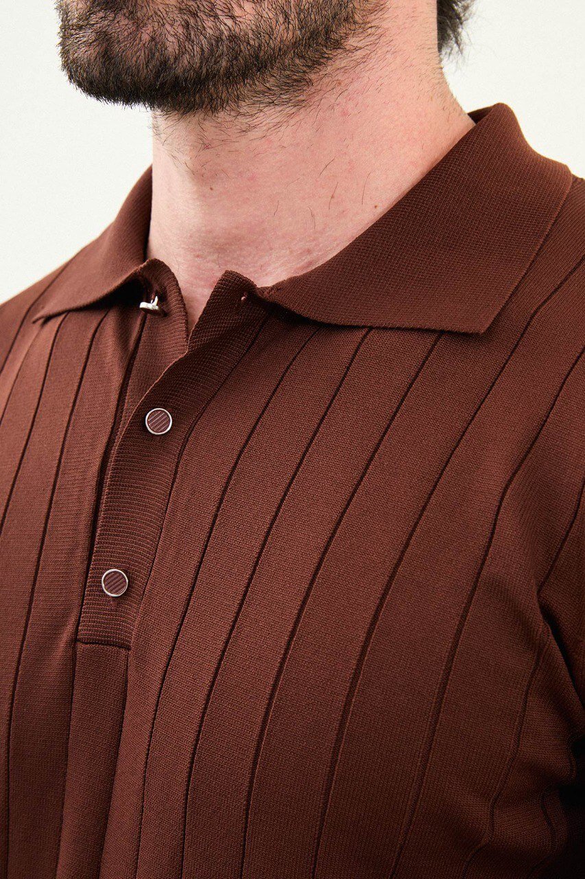 Men’s tile ribbed long-sleeve polo sweater in rust/terracotta with three-button placket, vertical rib knit texture, cotton-viscose stretch blend, styled with blue denim.