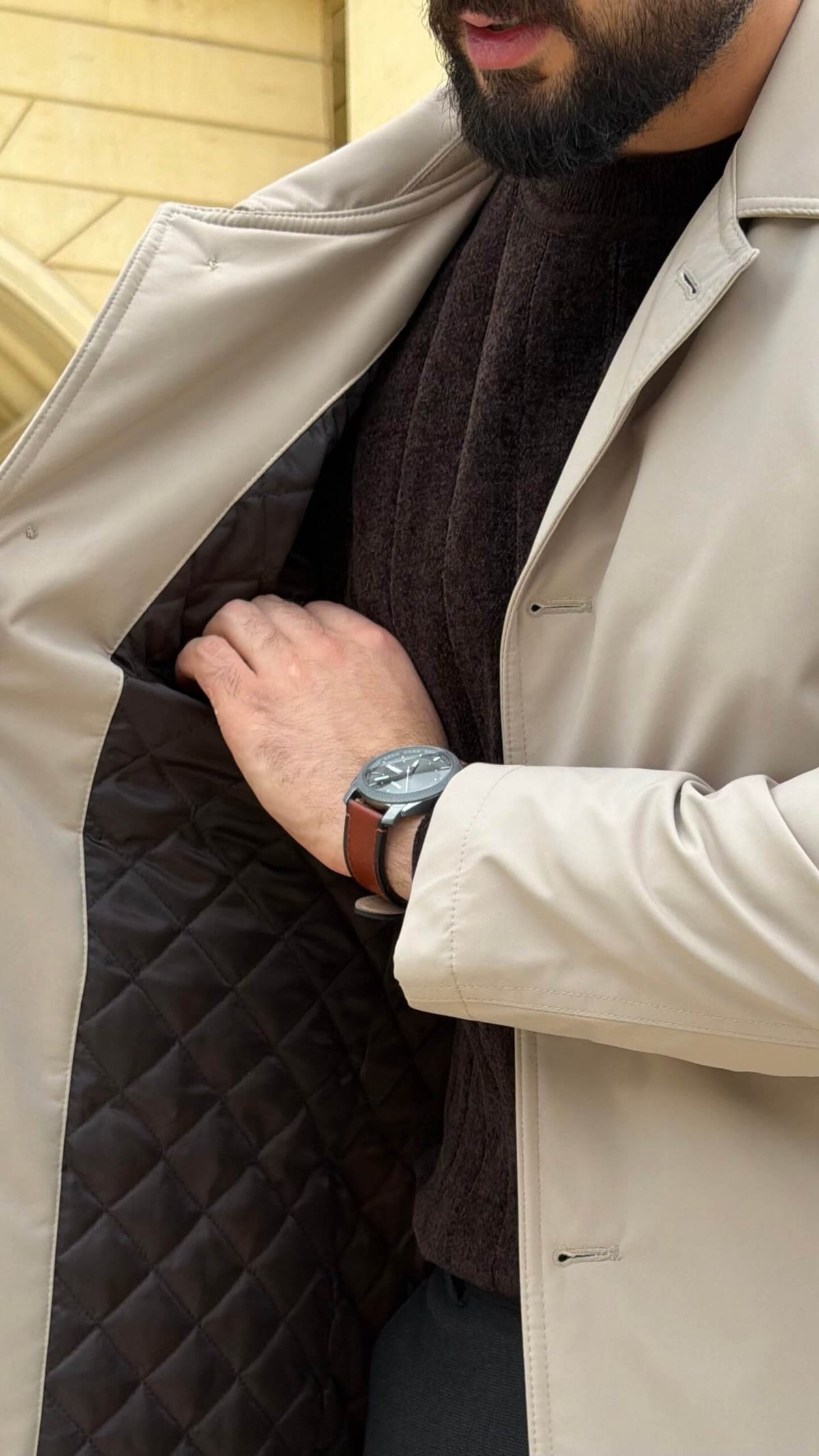 Men wearing a beige single breasted trench coat with button closure and side pockets