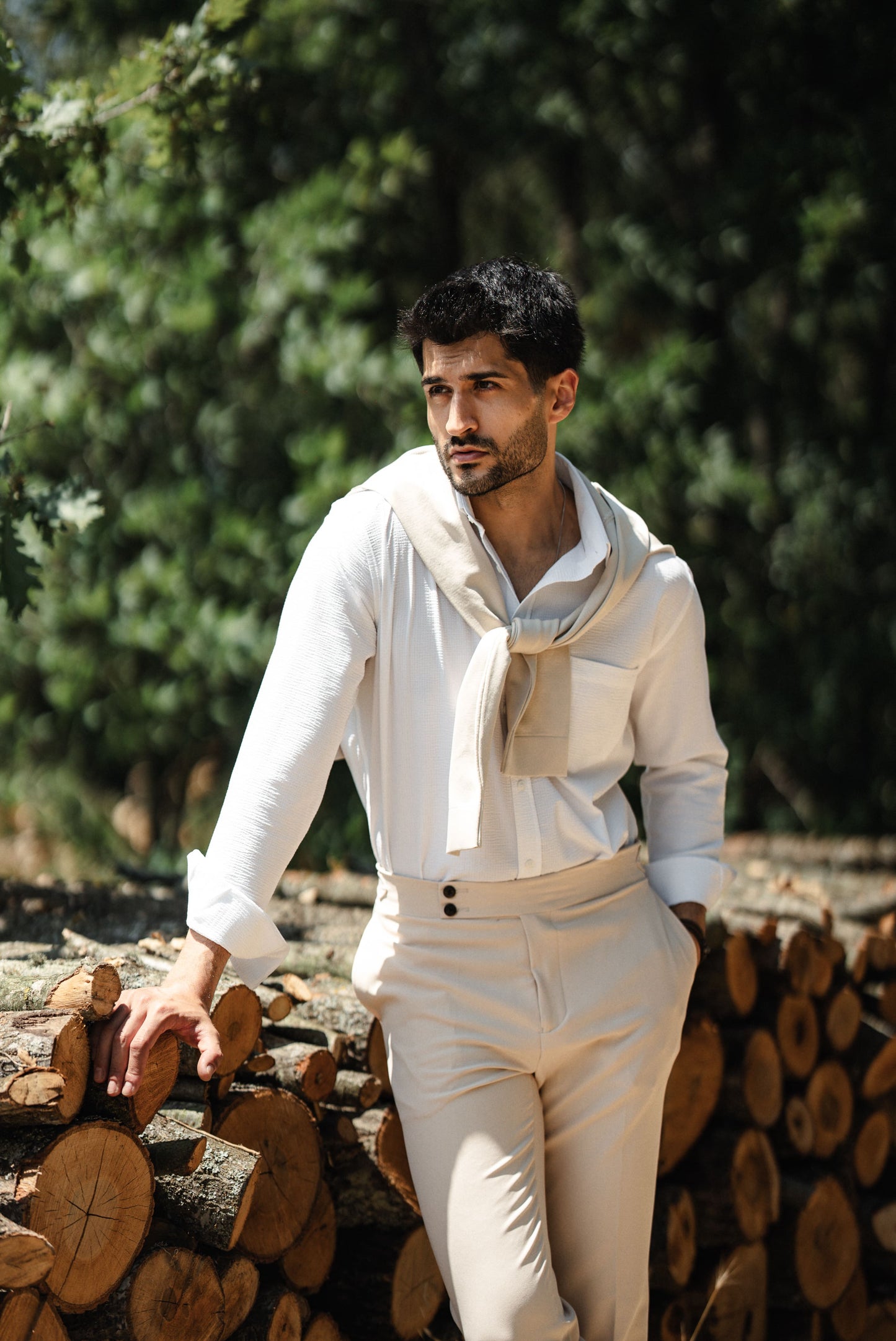 HolloMen Beige Linen Shirt worn by a man with a beige sweater draped over his shoulder, standing in a lush, natural outdoor setting.