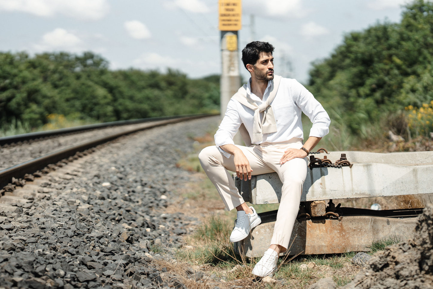 HolloMen Beige Linen Shirt worn by a man with a beige sweater draped over his shoulder, standing in a lush, natural outdoor setting.