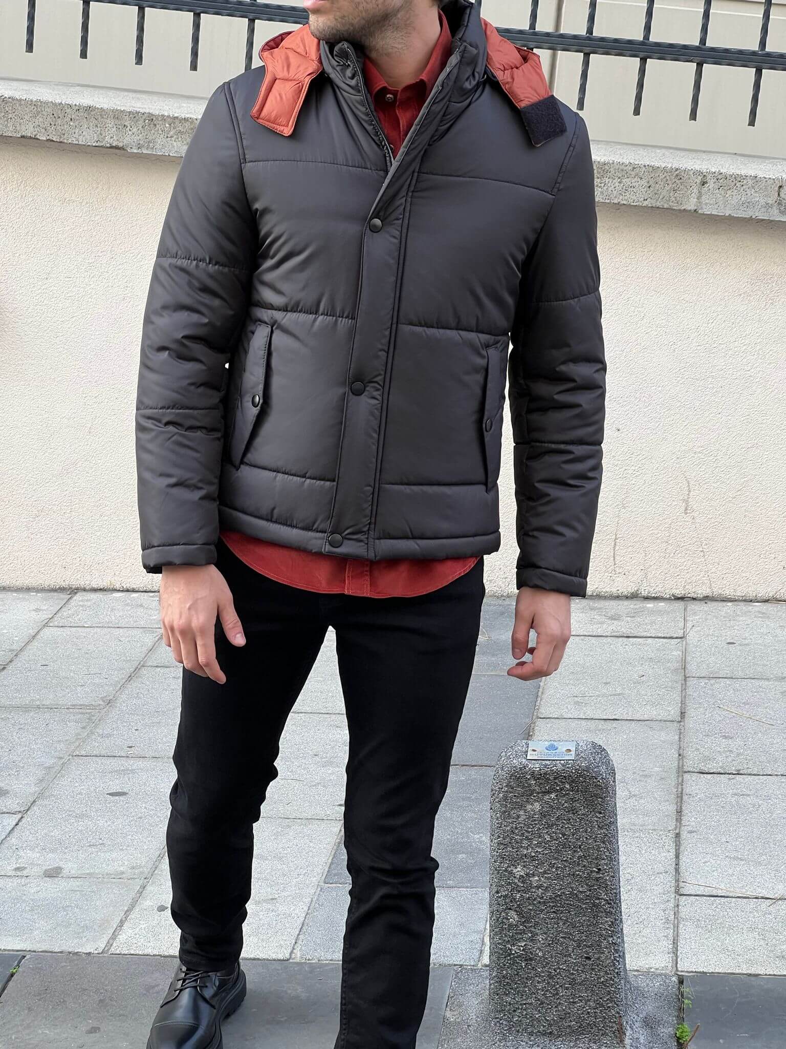 Elegance meets streetwear: Stylish young man in a black hooded coat, embodying casual cool.