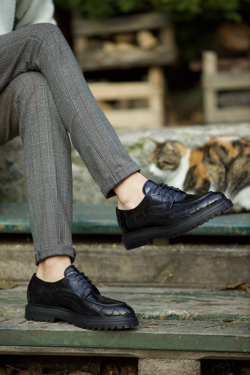 Black croc-embossed leather derby shoes with EVA sole, worn with tailored grey check trousers. 