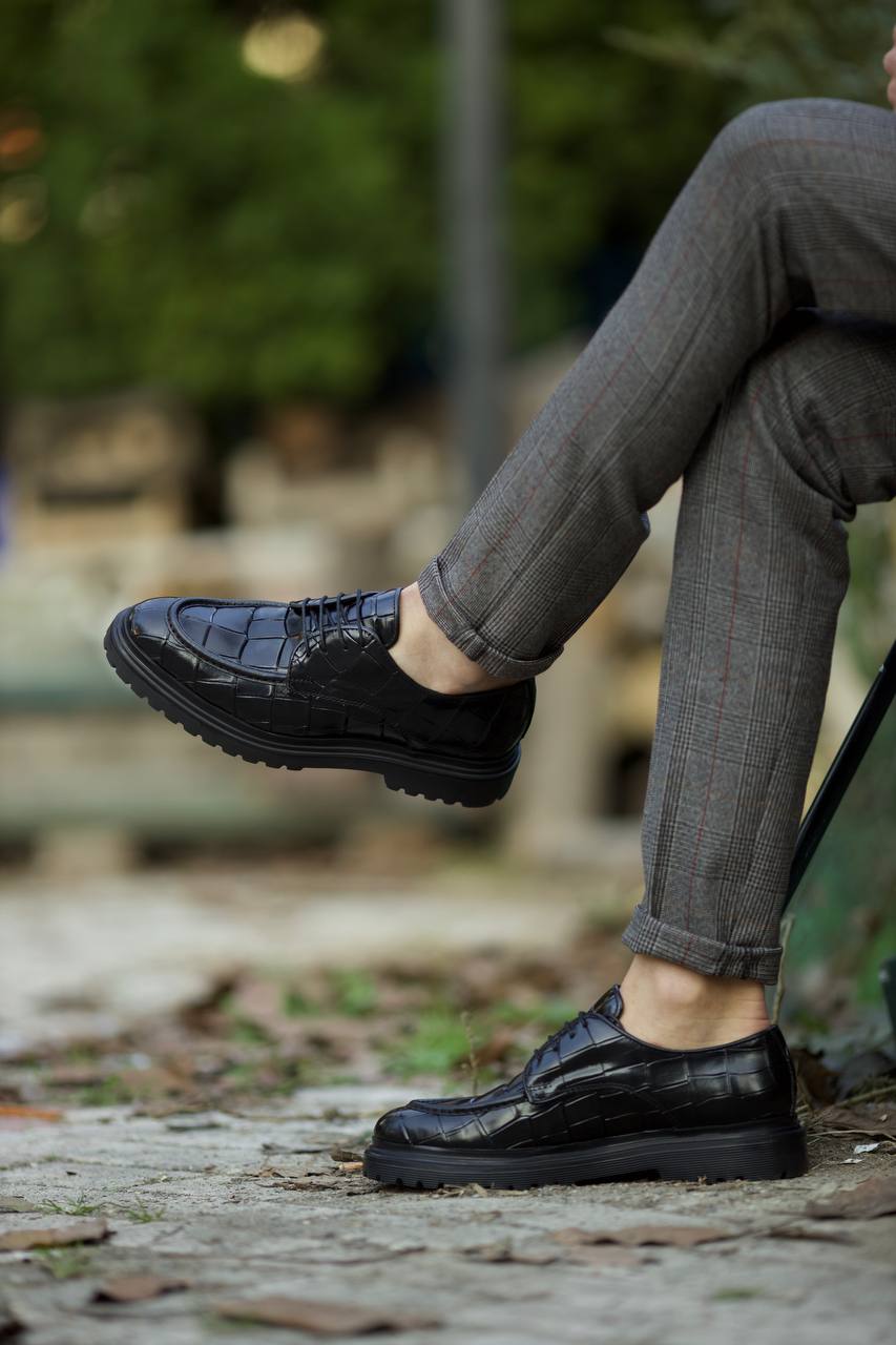 Black croc-embossed leather derby shoes with EVA sole, worn with tailored grey check trousers. 