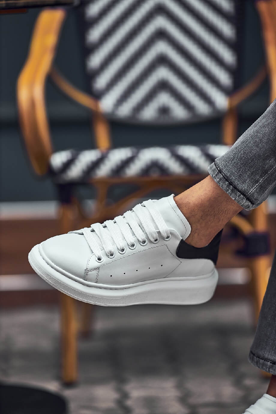 White leather sneakers with black heel detail worn with grey jeans