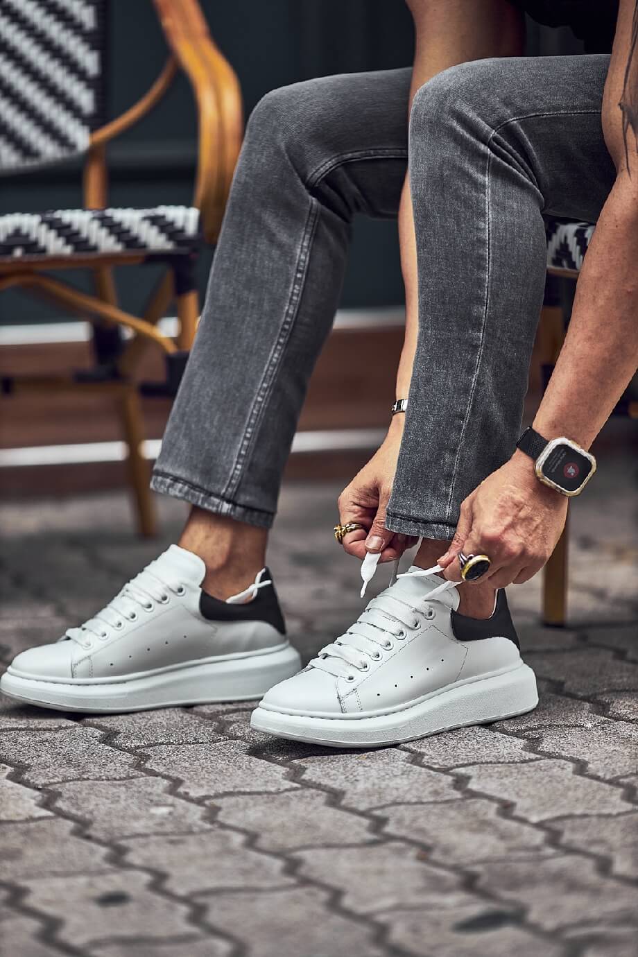 White leather sneakers with black heel detail worn with grey jeans