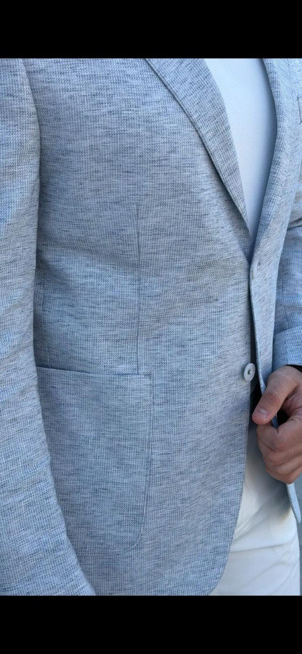 Men’s indigo blue slim-fit blazer styled with white trousers and a t-shirt, showcasing a lightweight textured fabric for smart-casual wear.