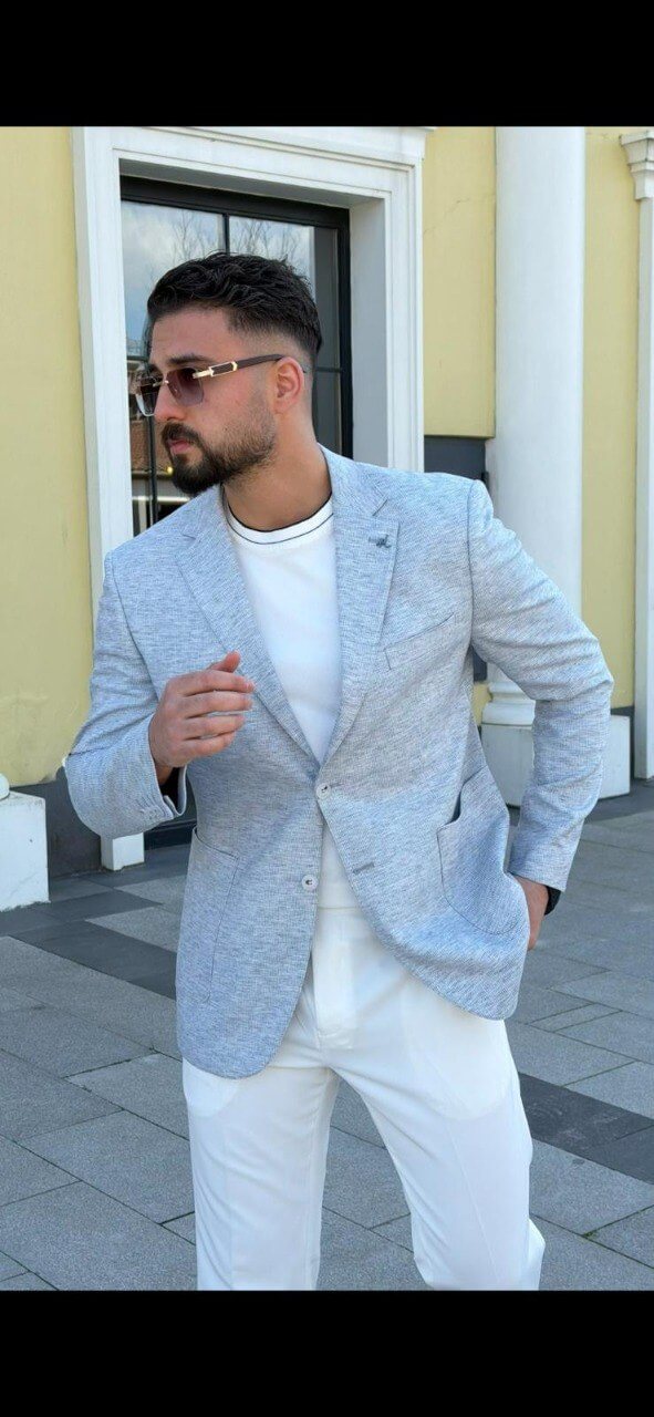 Men’s indigo blue slim-fit blazer styled with white trousers and a t-shirt, showcasing a lightweight textured fabric for smart-casual wear.