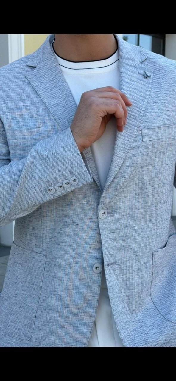 Men’s indigo blue slim-fit blazer styled with white trousers and a t-shirt, showcasing a lightweight textured fabric for smart-casual wear.