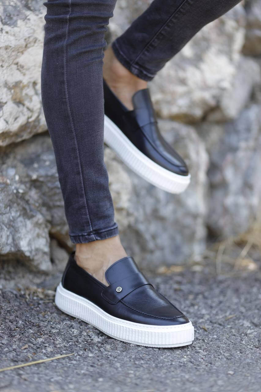 Navy blue leather slip-on loafers with white EVA soles, styled with skinny black jeans