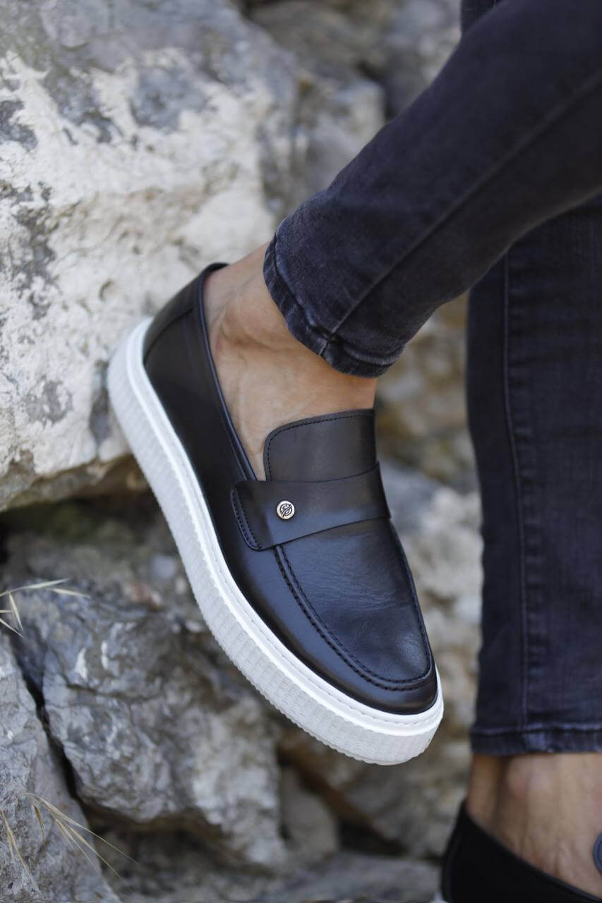 Navy blue leather slip-on loafers with white EVA soles, styled with skinny black jeans