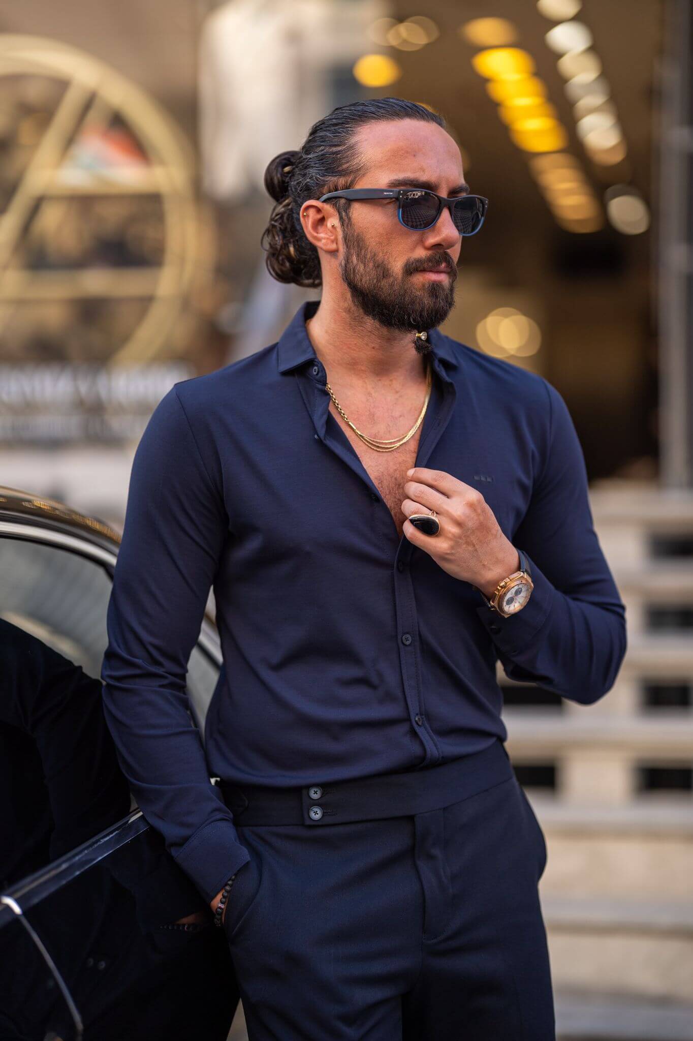 A confident male model wearing a stylish navy blue shirt, exuding charisma and sophistication.