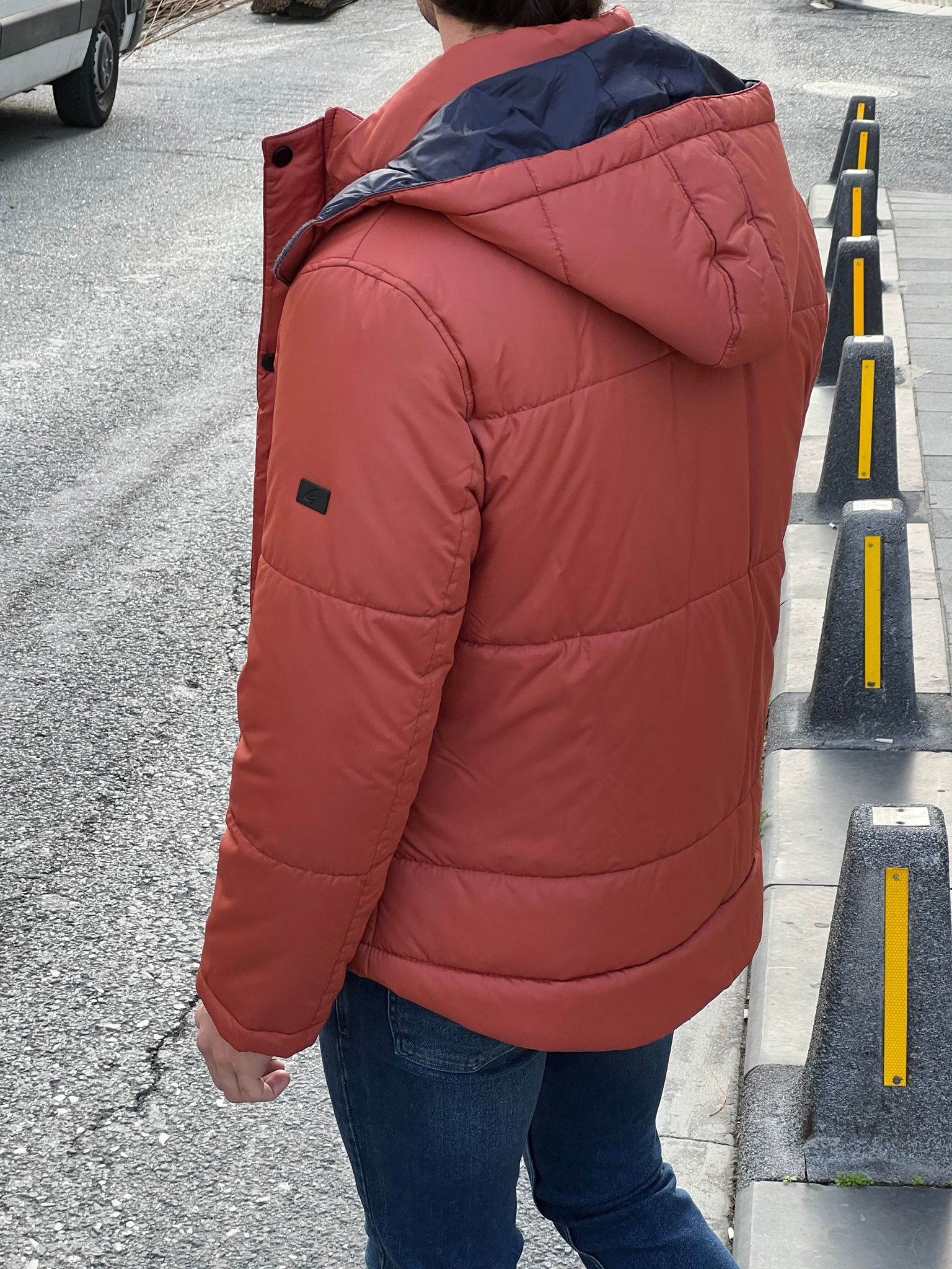 Bold and trendy: our model showcasing an eye-catching orange hooded jacket.