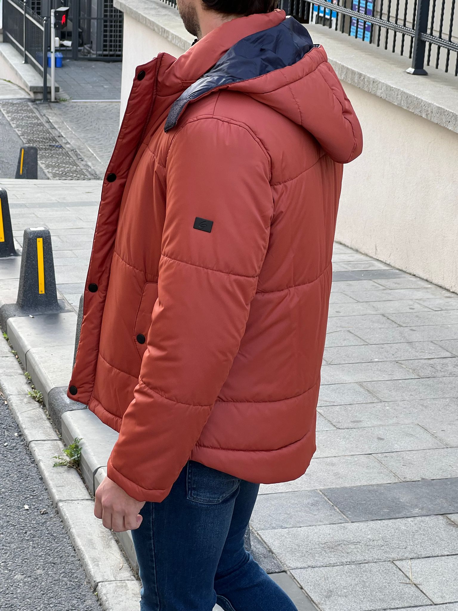 Bold and trendy: our model showcasing an eye-catching orange hooded jacket.