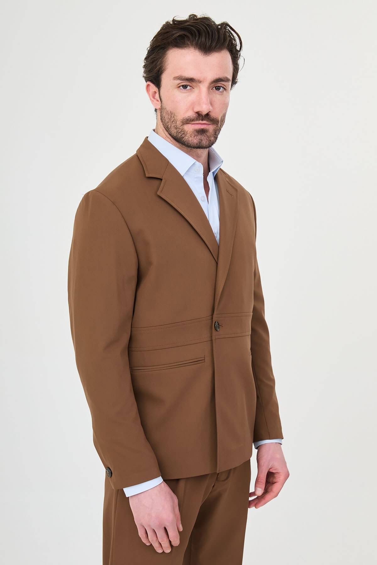Man wearing a camel slim-fit two-piece suit, tailored for summer, standing outdoors, front view.