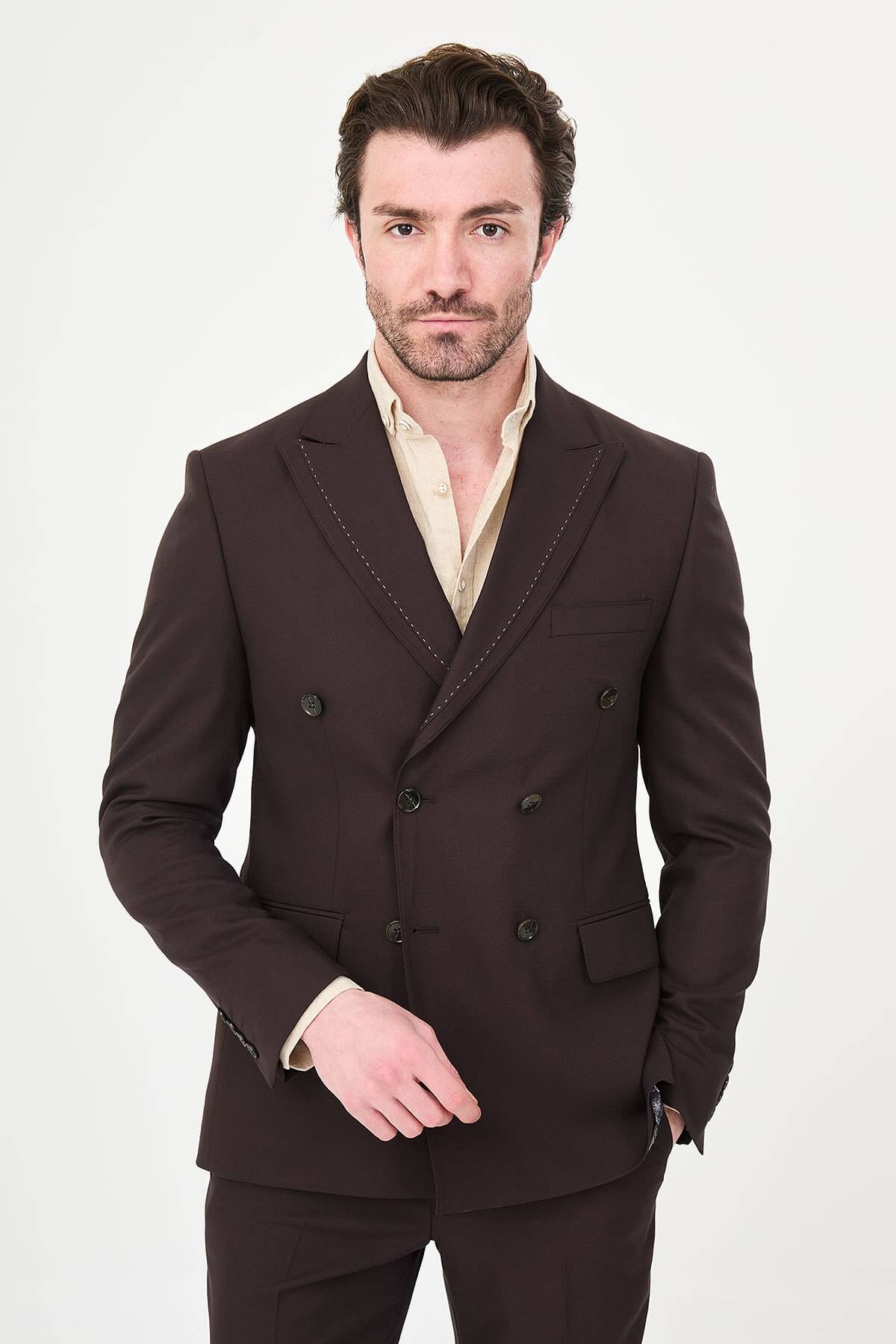 a brown slim-fit double-breasted linen-blend suit with peak lapels, contrast pick stitching, matching trousers, and an open-collar cream shirt.