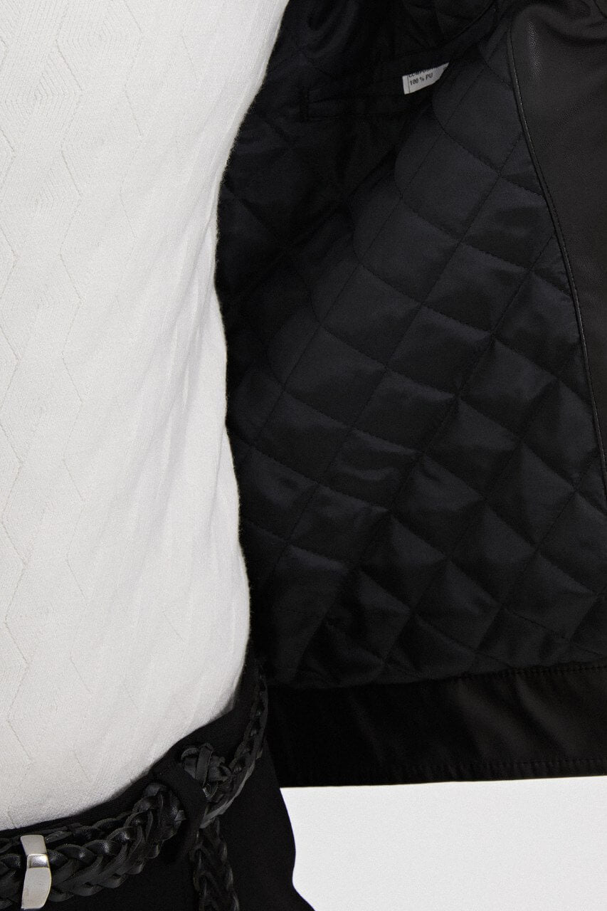 Men's black leather-look jacket styled with a cream knit sweater and black trousers.