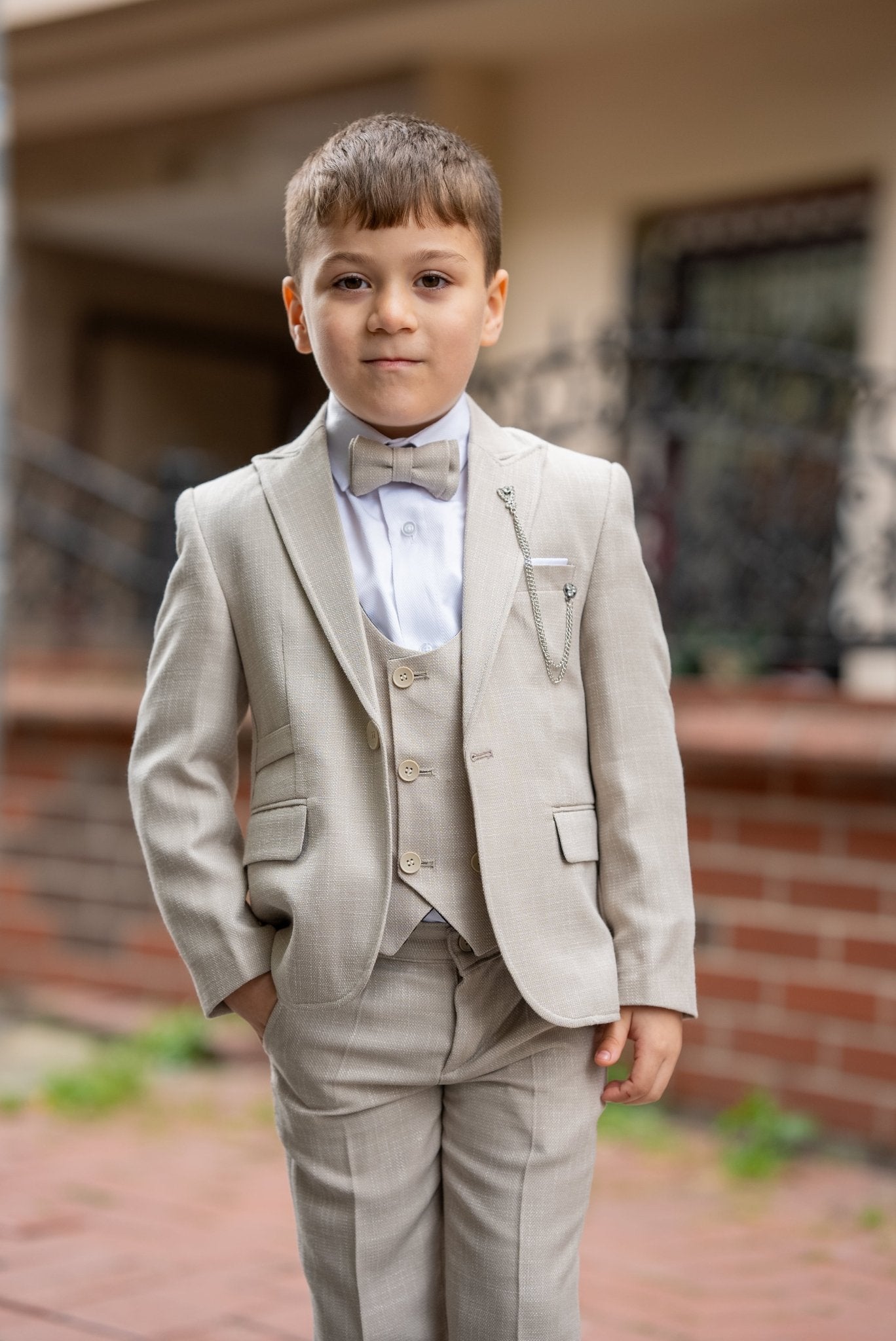 Father and his two sons walking down a street in matching beige tuxedos with elegant bow ties, exuding confidence and style during a formal occasion.