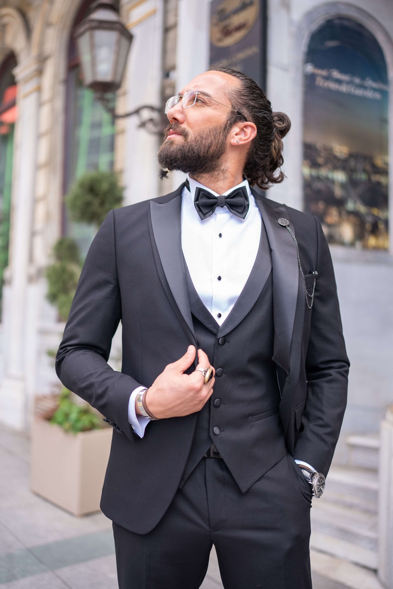 Black satin-collar men’s tuxedo in slim fit, styled with a vest, bow tie, and formal pants – a 5-piece formal set ideal for weddings, galas, and luxury events.