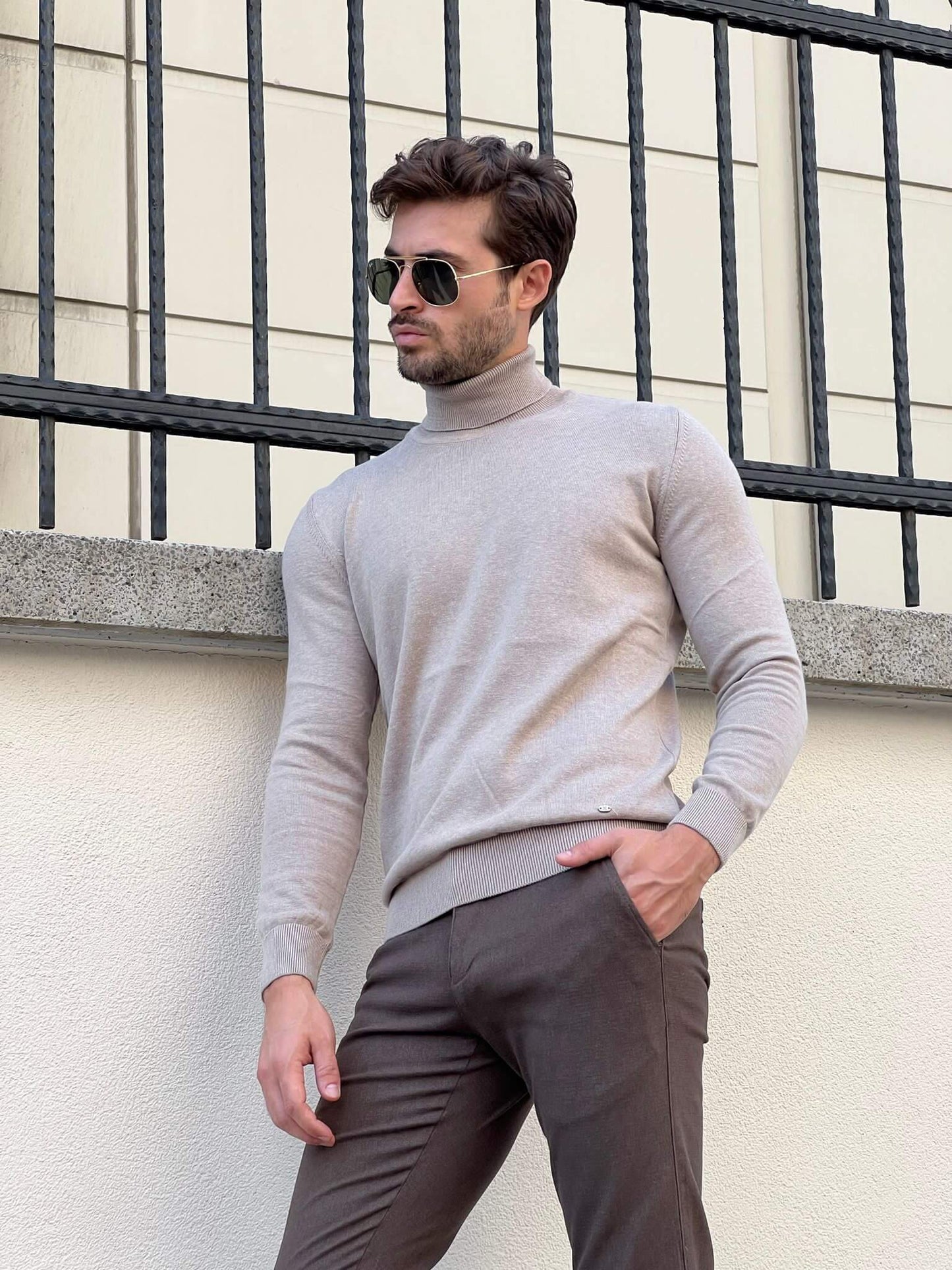 A beige turtleneck sweater with a folded collar, showcasing its soft, ribbed texture