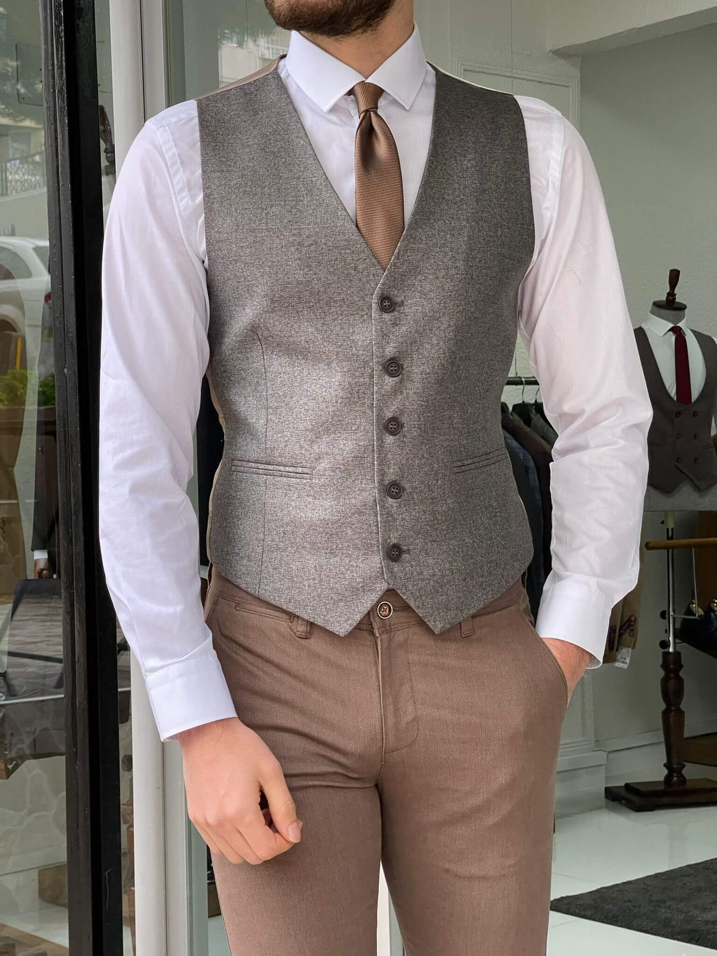 A close-up of a beige waistcoat with buttons and a V-neckline