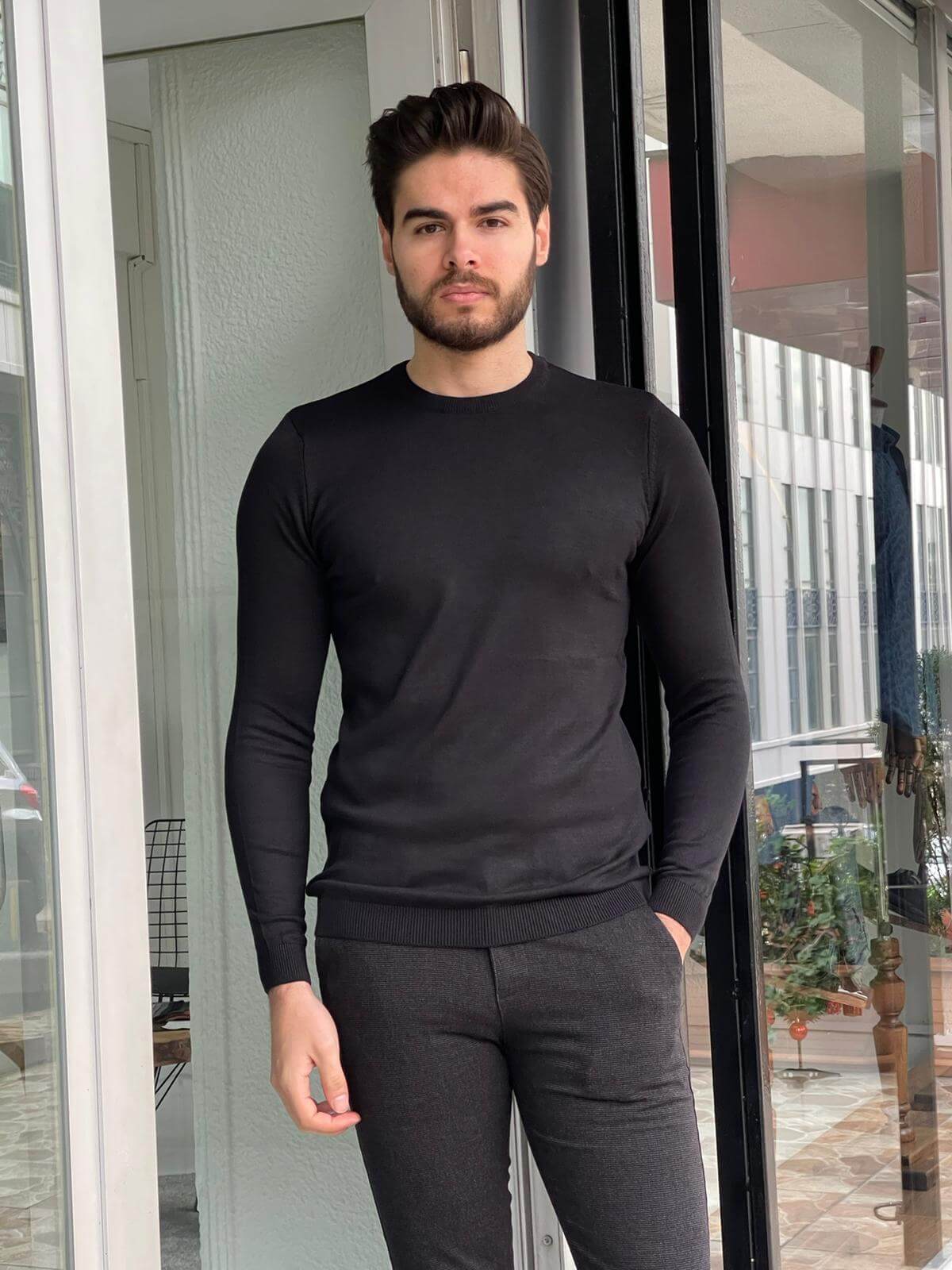 A black crewneck sweater with a relaxed fit worn by a model